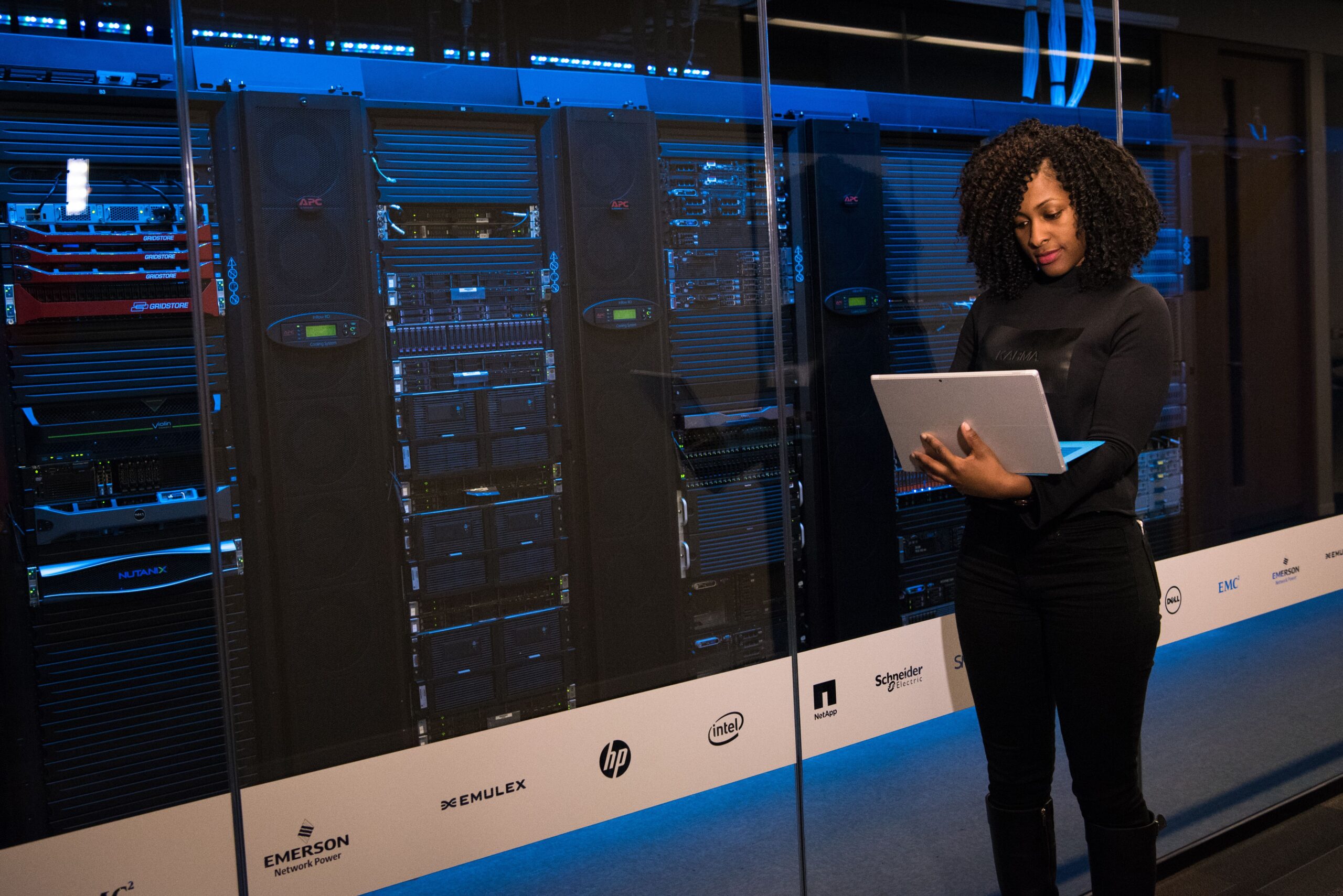 Data engineer monitoring server racks in a data center using a laptop, symbolizing Spark 4.2 deployment and cluster management.