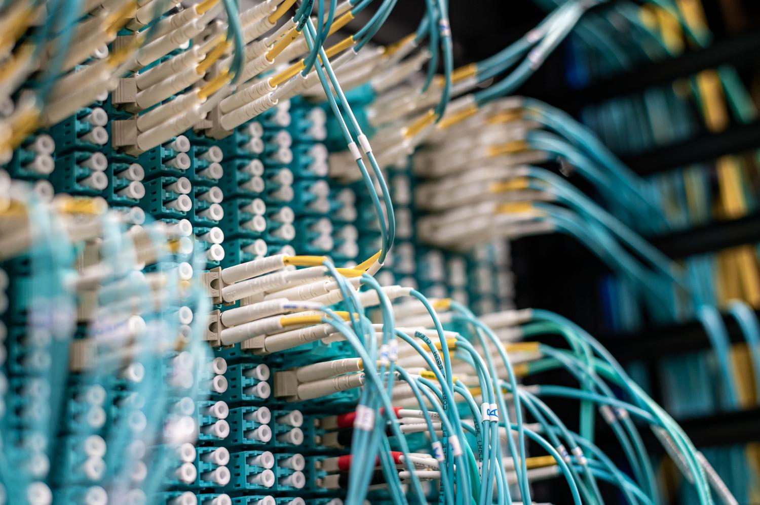 Detalle de cables de fibra óptica conectados a paneles de parcheo en un centro de datos, ilustrando la capa física de una arquitectura de red.