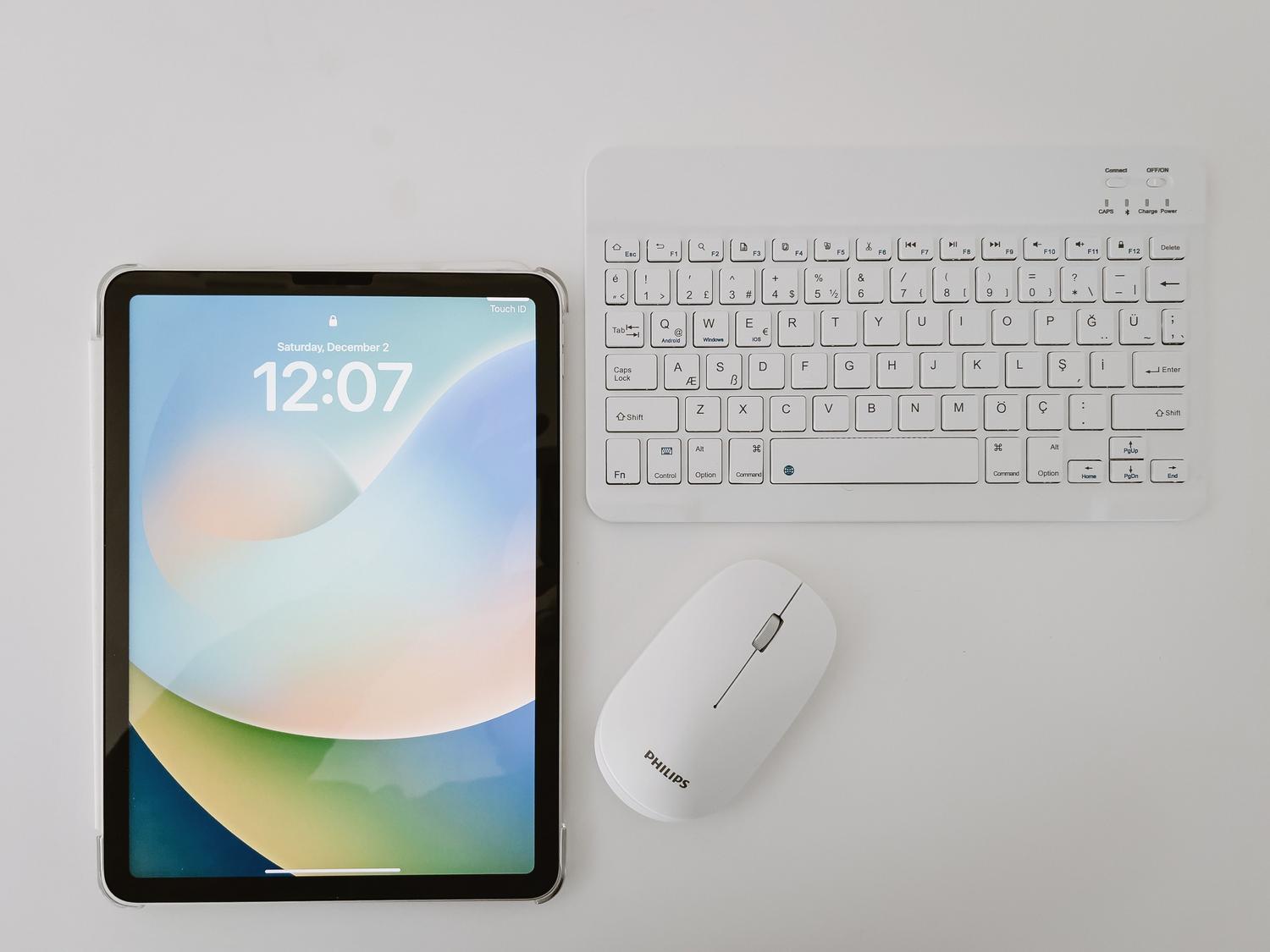 Configuración de estación de trabajo con tablet, teclado inalámbrico y ratón sobre un escritorio limpio.