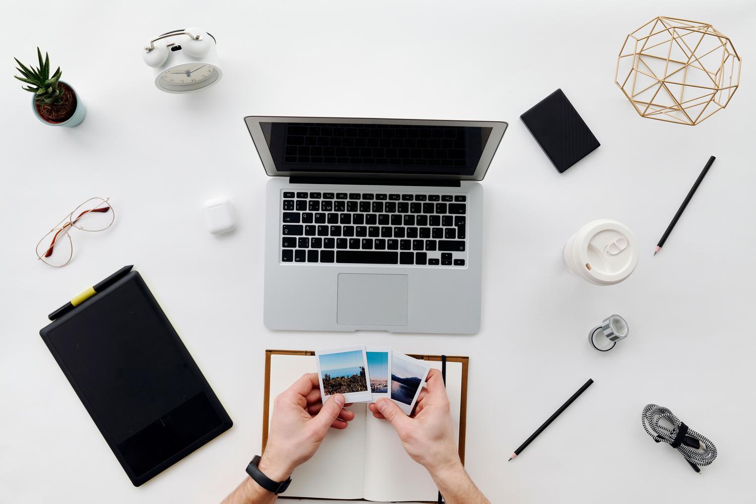 Espacio de trabajo organizado con portátil y fotografías, representando el control y orden digital