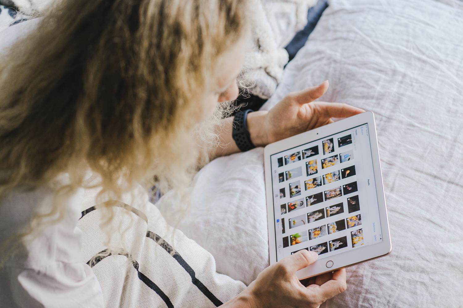Persona revisando su galería de fotos en una tablet desde la comodidad del hogar