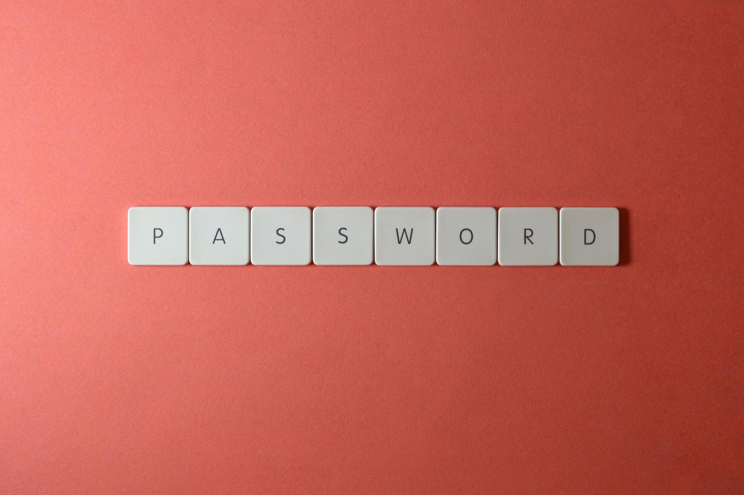 Teclas de teclado blanco formando la palabra 'PASSWORD' sobre un fondo coral, representando la seguridad de las contraseñas.