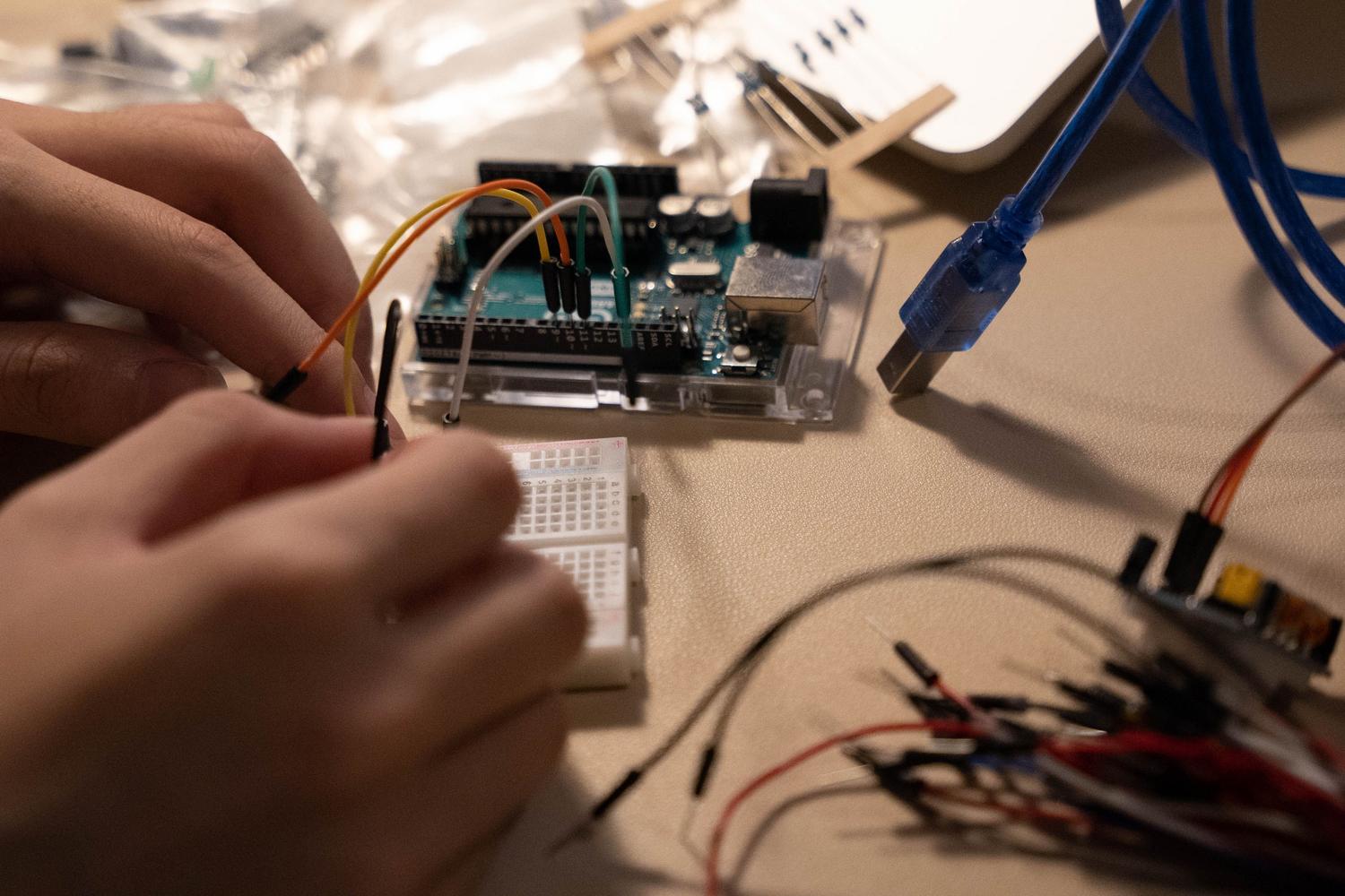 Primer plano de manos ensamblando componentes electrónicos y cables en una protoboard para un proyecto DIY de domótica. Primer plano de manos ensamblando componentes electrónicos y cables en una protoboard para un proyecto DIY de domótica.