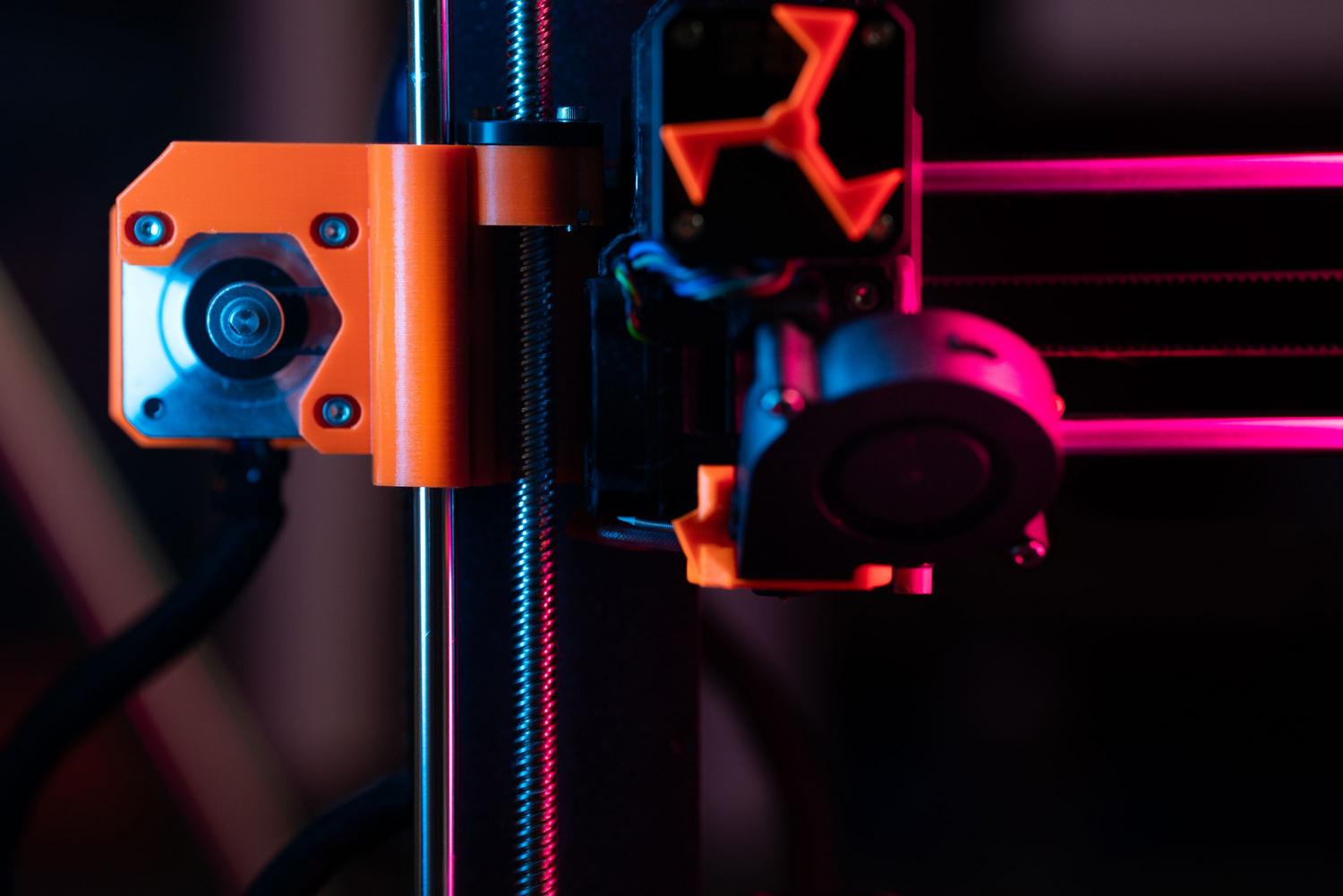 Detalle técnico del mecanismo del extrusor de una impresora 3D bajo una iluminación vibrante.