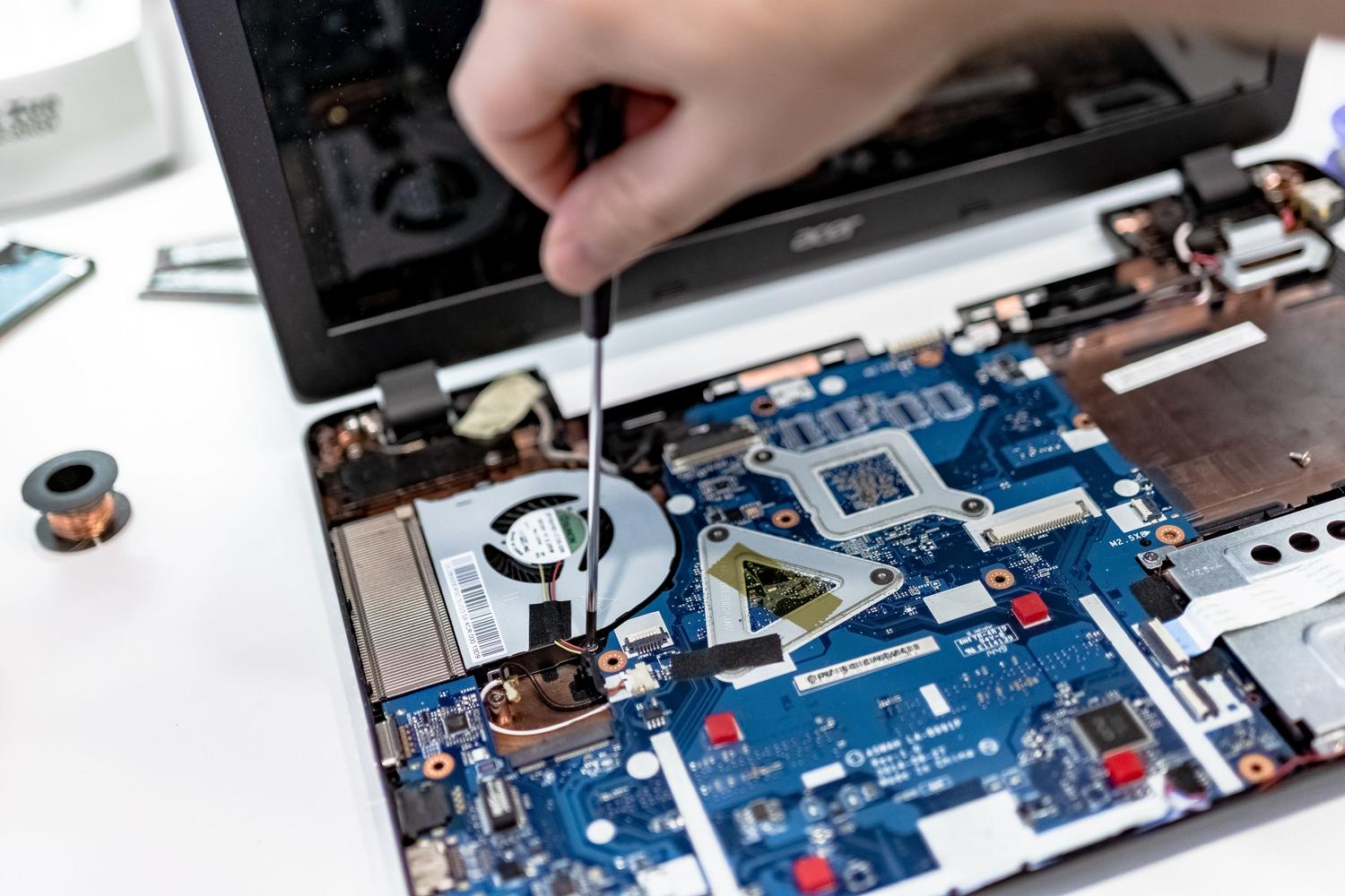Técnico utilizando un destornillador para acceder a la placa base de un portátil antiguo