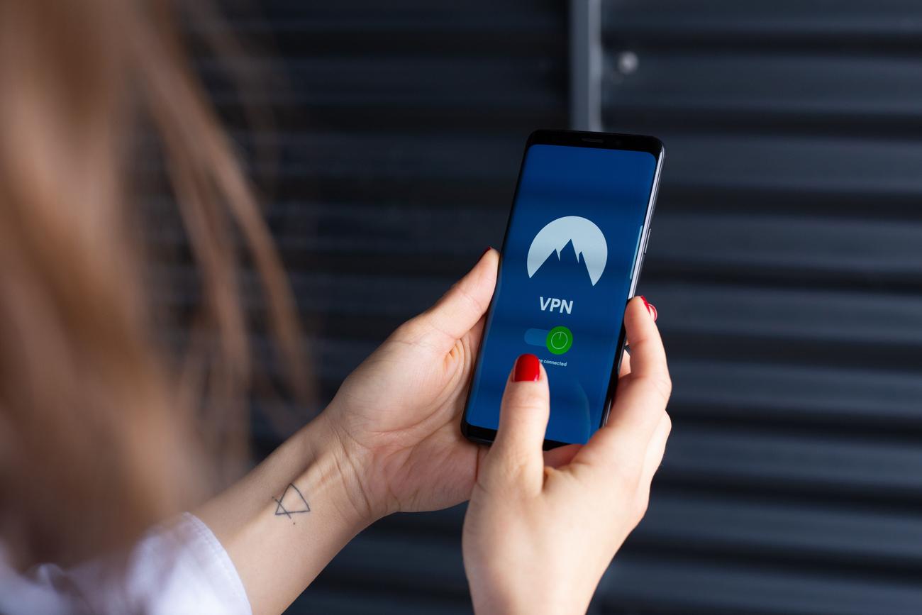 Primer plano de unas manos utilizando una aplicación de VPN en un smartphone, destacando la facilidad de desbloquear webs desde el móvil.