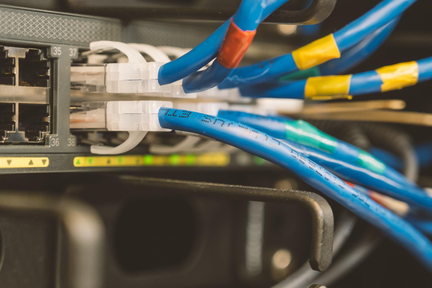 Cables Ethernet azules conectados a un switch de red, representando la configuración de WAN y LAN.