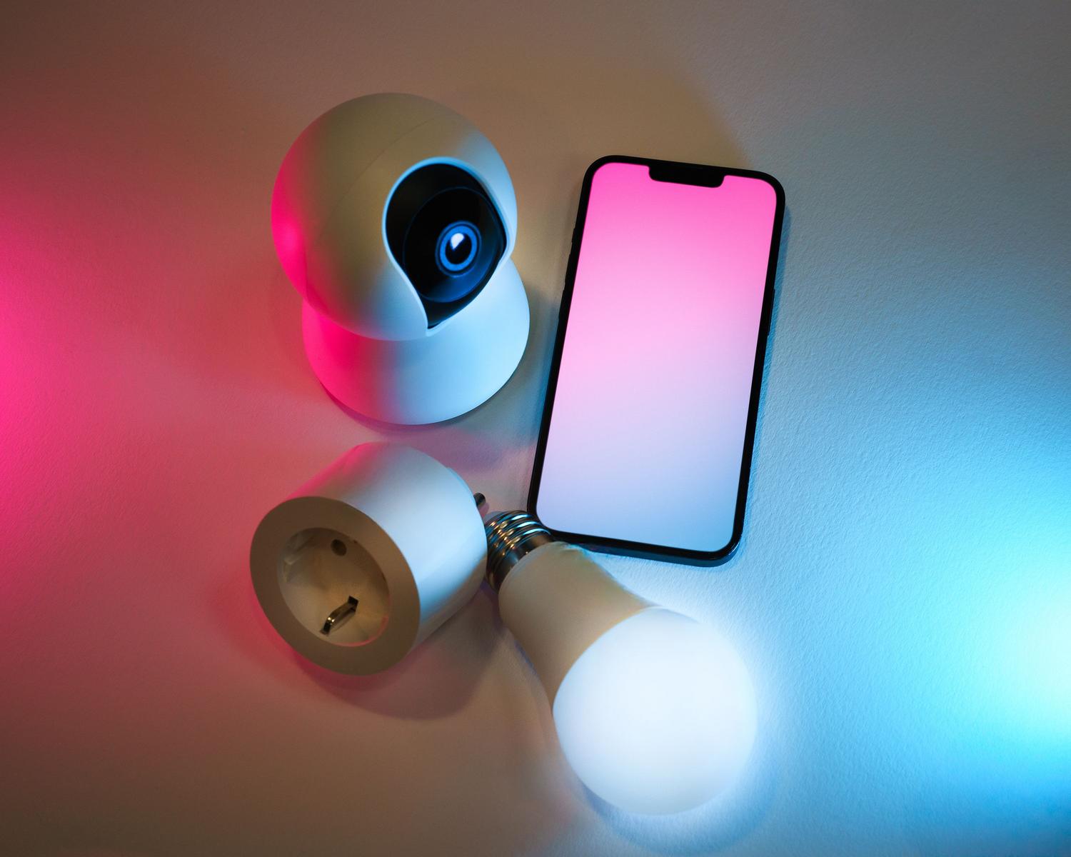 Conjunto de dispositivos IoT como bombillas inteligentes, cámaras y enchufes controlados desde un móvil