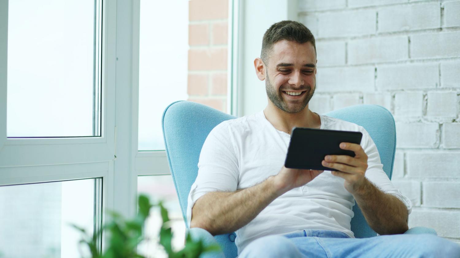 Hombre utilizando una tablet en su hogar para configurar los ajustes de red de su router