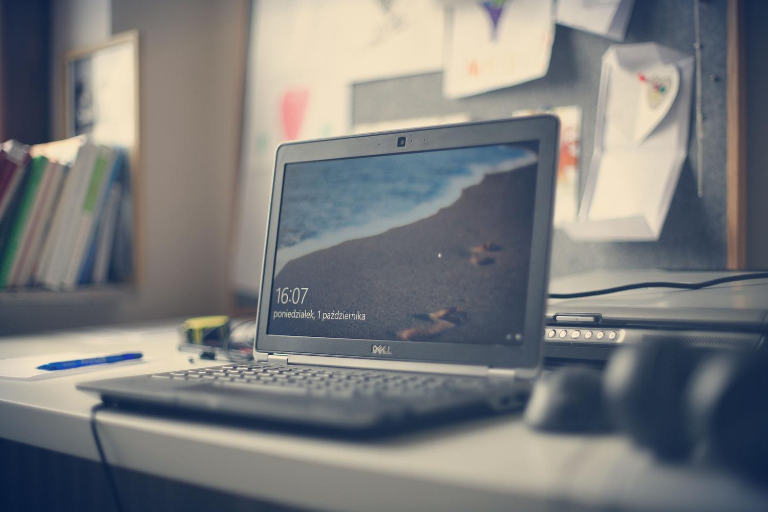 Espacio de trabajo contemporáneo con un portátil Dell sobre un escritorio blanco, simbolizando la claridad y el alto rendimiento.