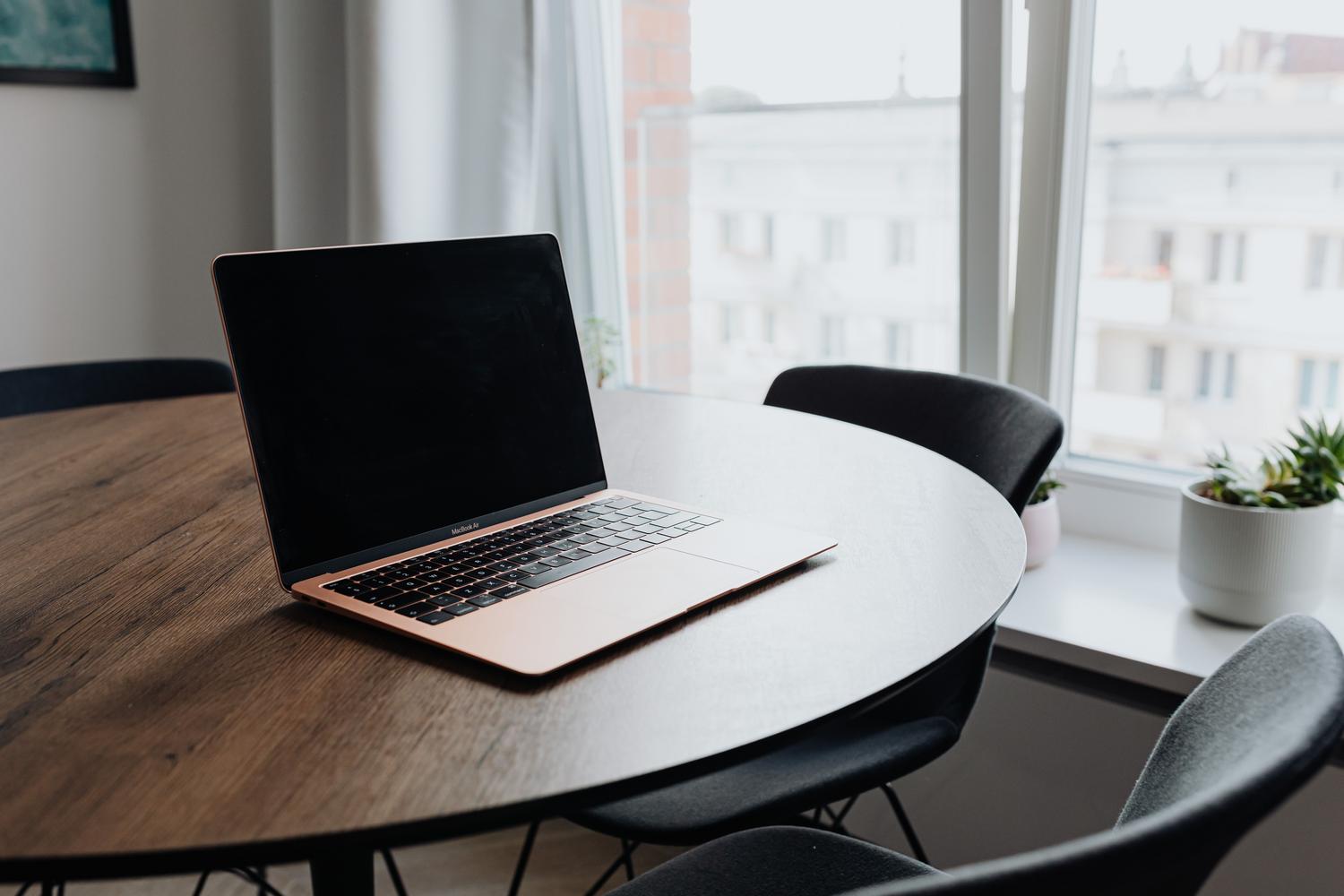 Espacio de trabajo acogedor con un portátil sobre una mesa de madera, reflejando un ambiente de mantenimiento técnico y orden.