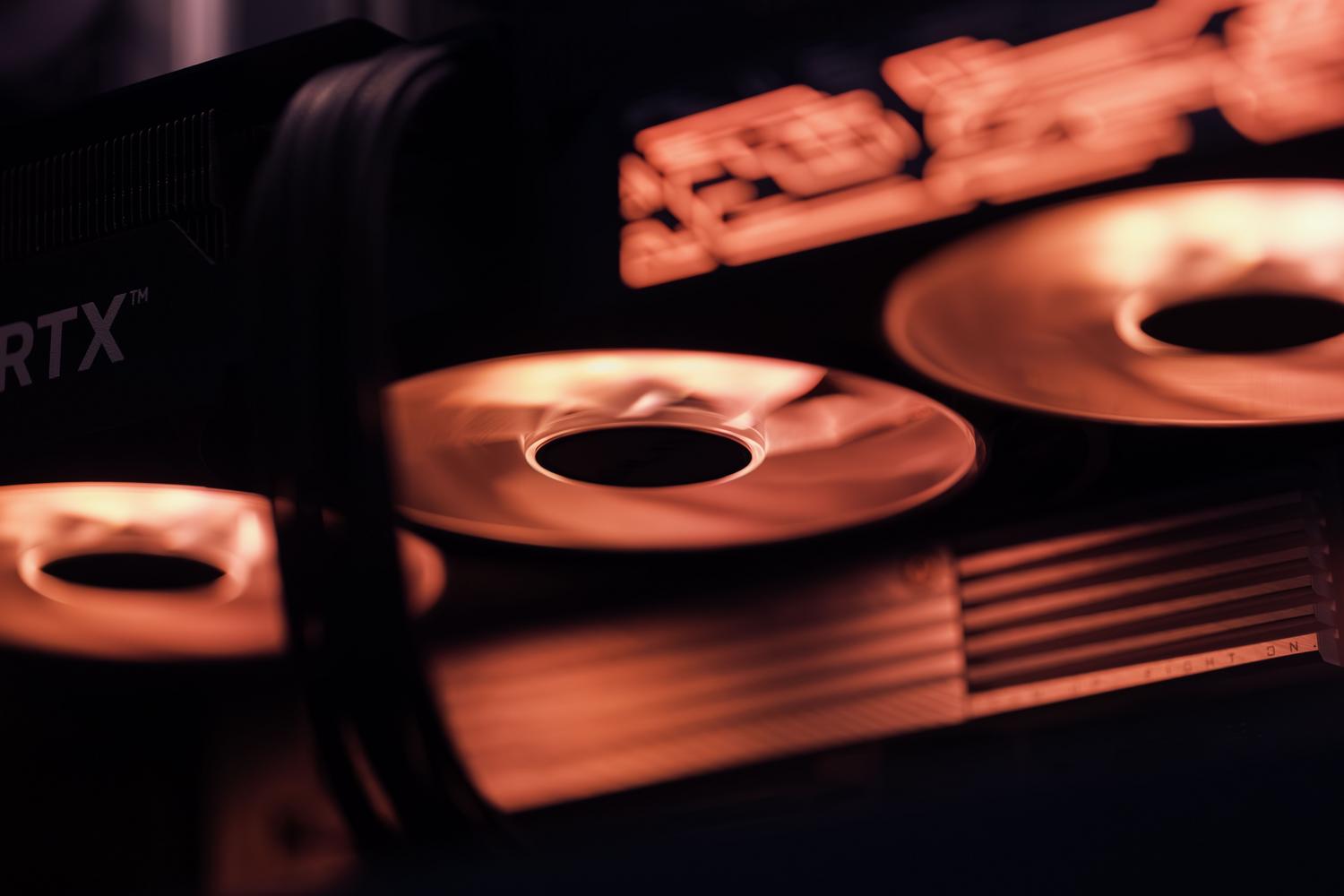 Primer plano de los ventiladores de una tarjeta gráfica gaming con iluminación LED roja, ideal para ilustrar el sistema de refrigeración y el sobrecalentamiento. Primer plano de los ventiladores de una tarjeta gráfica gaming con iluminación LED roja, ideal para ilustrar el sistema de refrigeración y el sobrecalentamiento.
