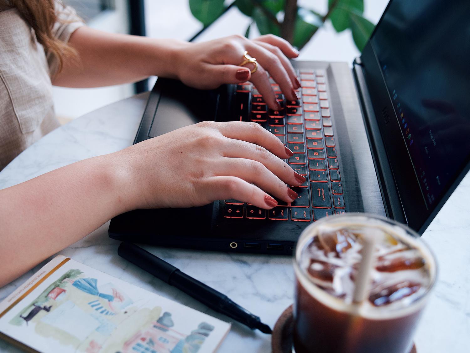 Mujer joven escribiendo en un ordenador portátil en una cafetería, representando la generación de contenido escrito y creatividad. Mujer joven escribiendo en un ordenador portátil en una cafetería, representando la generación de contenido escrito y creatividad.