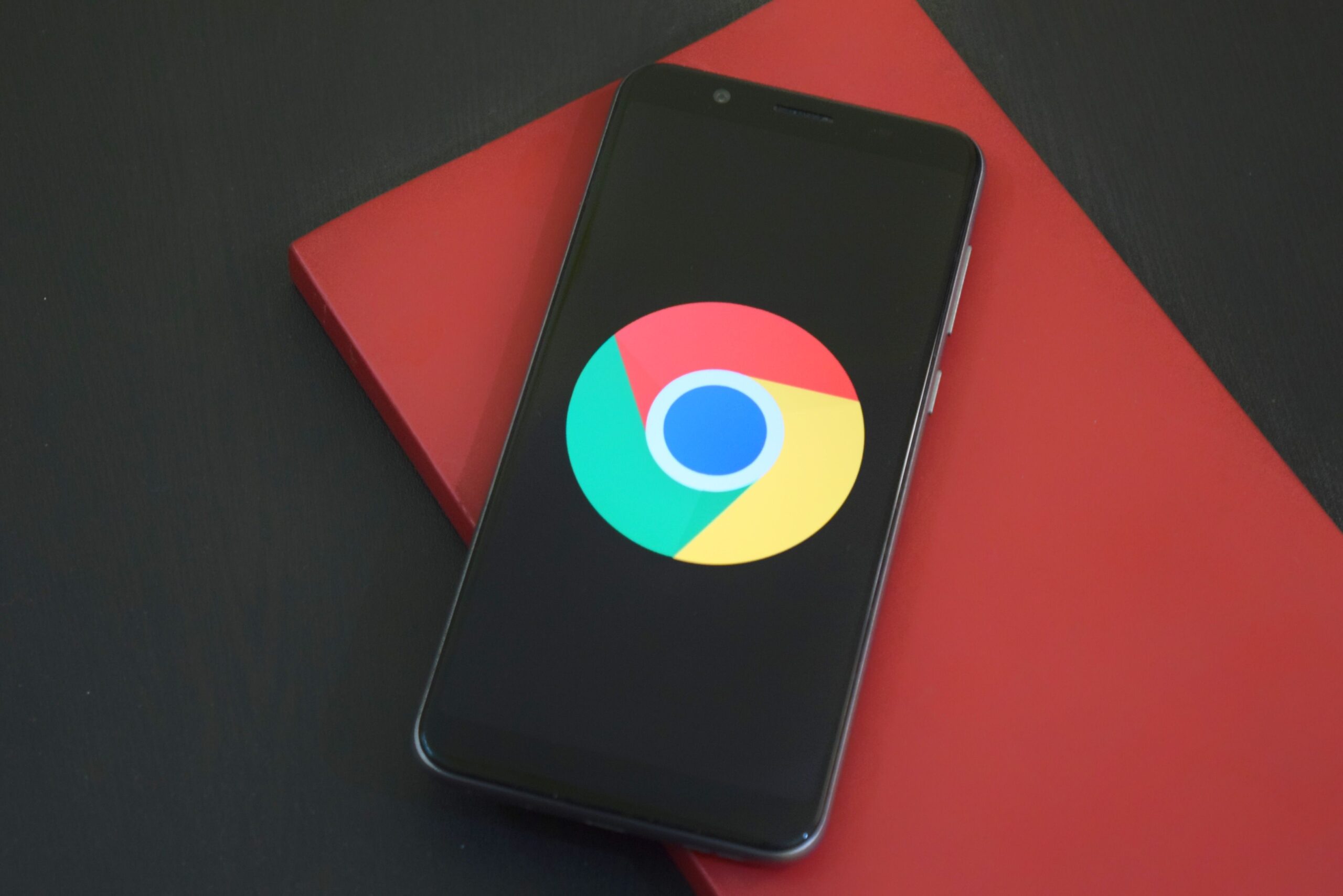 Smartphone con el logo de Google Chrome en pantalla sobre un cuaderno rojo
