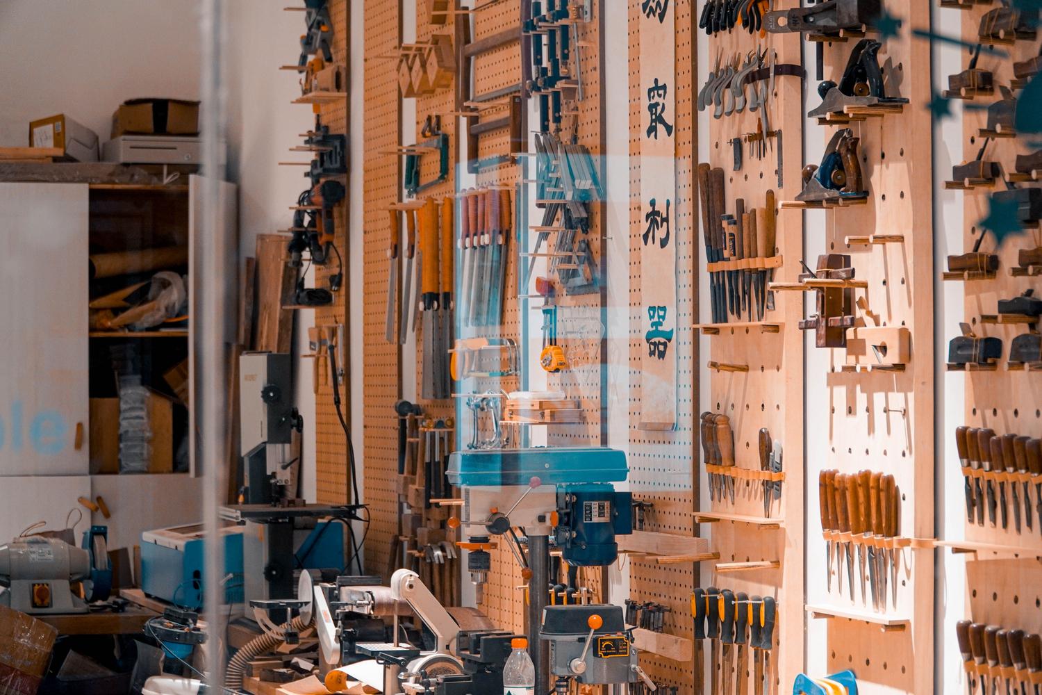 Taller organizado con herramientas colgadas en paneles de madera perforada Taller organizado con herramientas colgadas en paneles de madera perforada