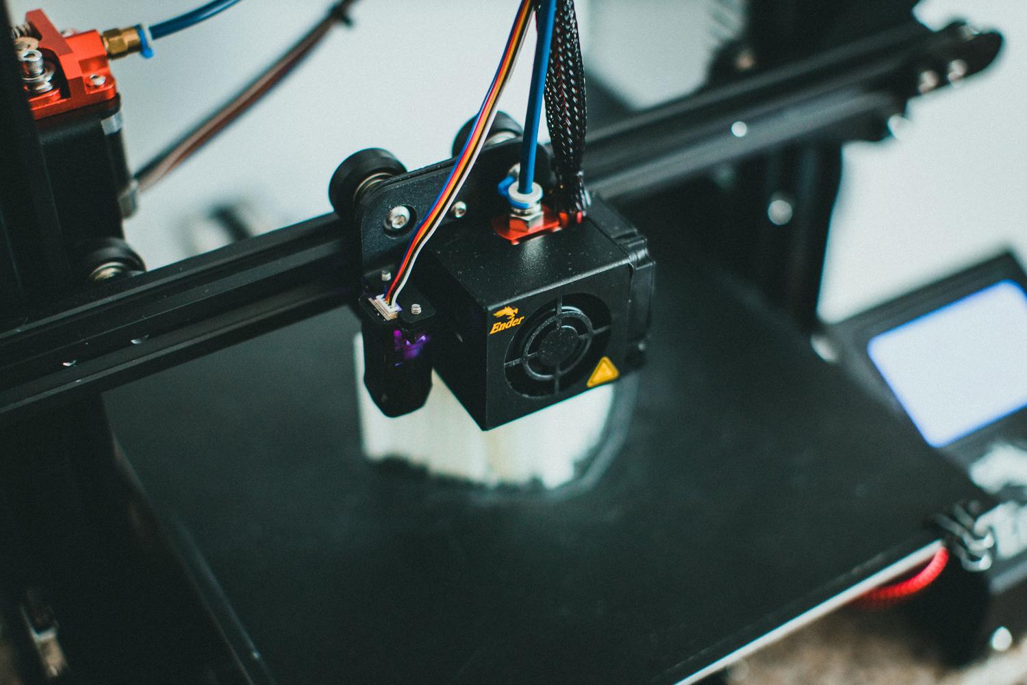 Primer plano de una impresora 3D FDM fabricando una pieza blanca para un teclado mecánico. Primer plano de una impresora 3D FDM fabricando una pieza blanca para un teclado mecánico.