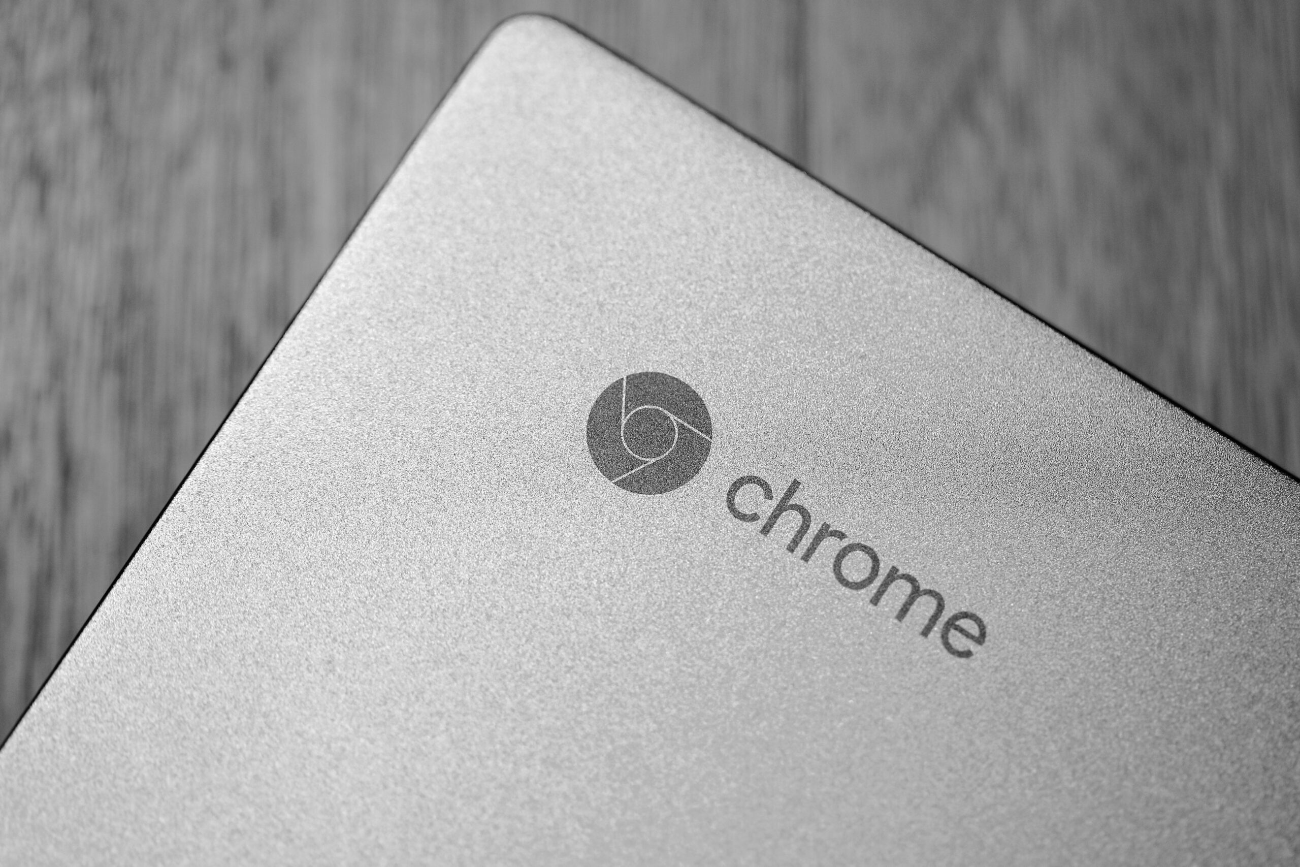 Detalle en blanco y negro del logotipo de Chrome en un portátil, útil para las secciones de configuración del sistema operativo.