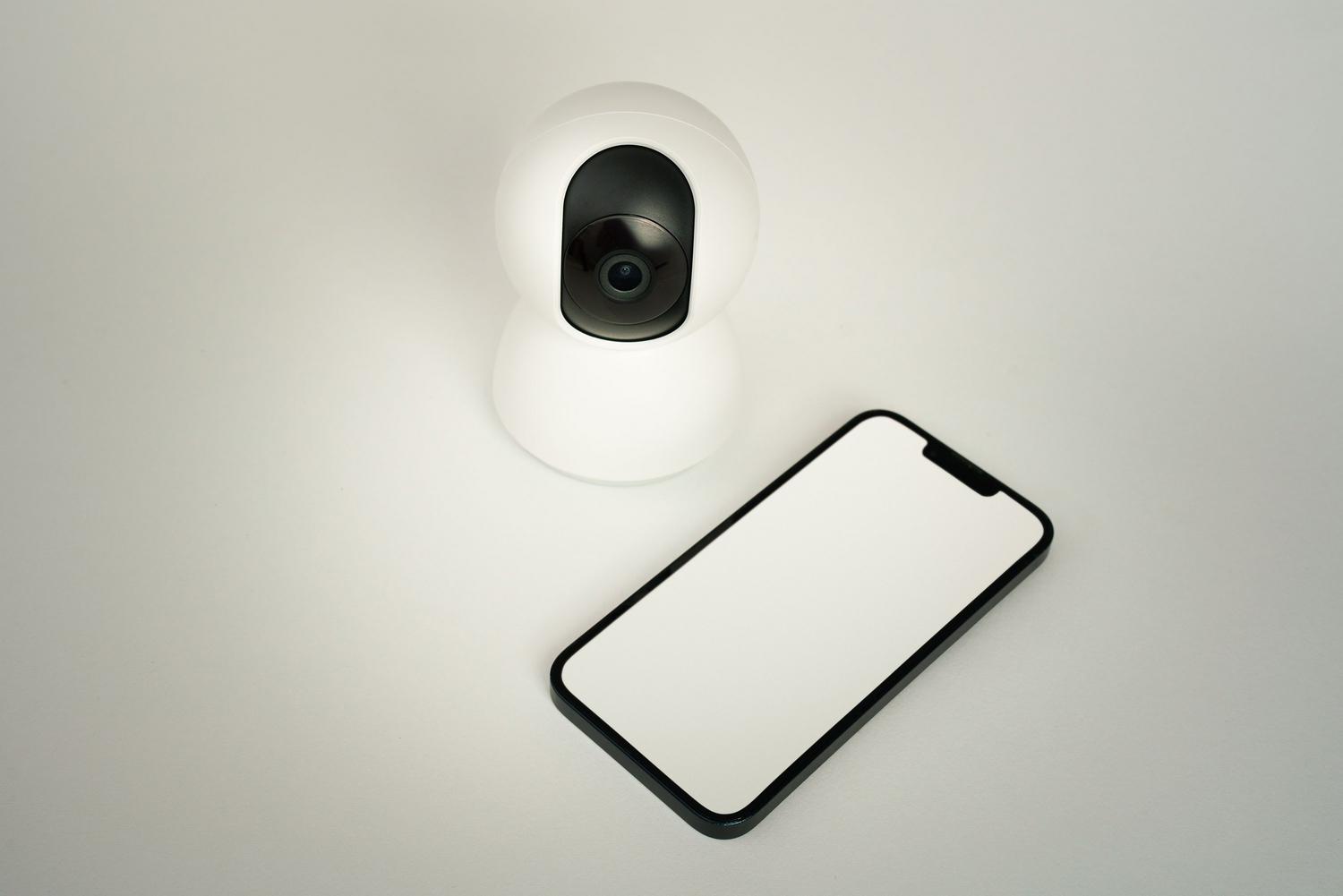 Conjunto de cámara de seguridad inteligente y smartphone sobre un fondo blanco, simbolizando la integración total del sistema de vigilancia.