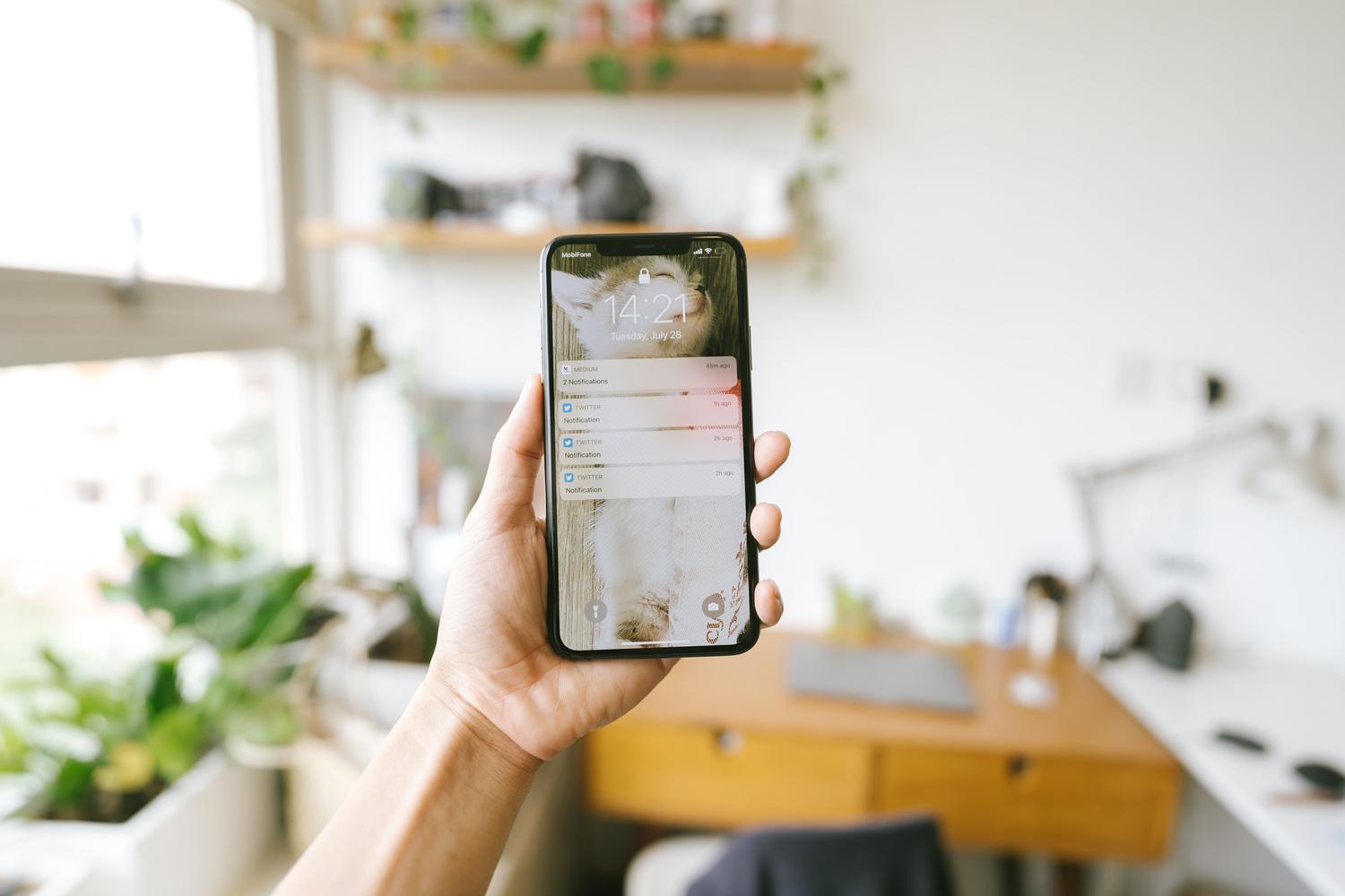 Primer plano de una mano sosteniendo un smartphone con enfoque en las notificaciones de la pantalla, ilustrando las alertas de seguridad en tiempo real.