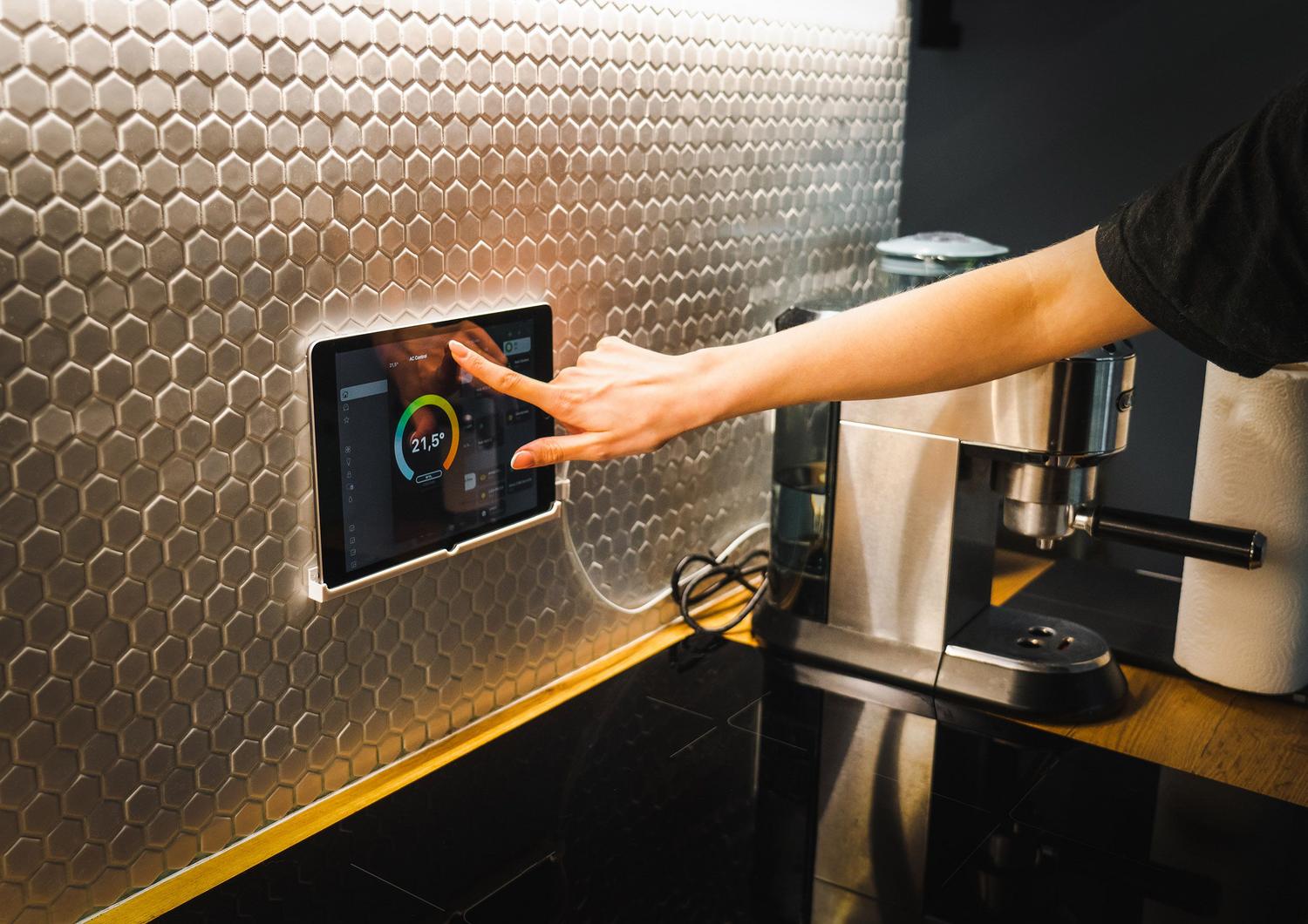 Persona utilizando una tablet para controlar los dispositivos de su hogar inteligente a través de una interfaz digital.