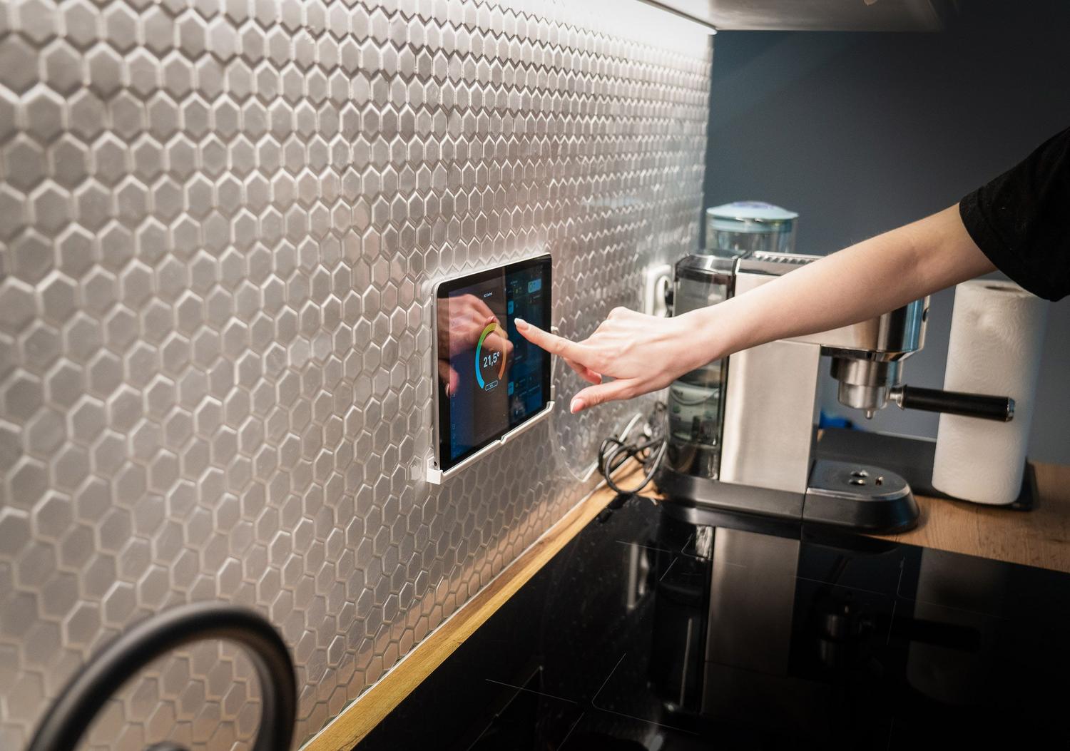 Panel de control domótico integrado en la pared de una cocina moderna para gestionar el hogar inteligente.