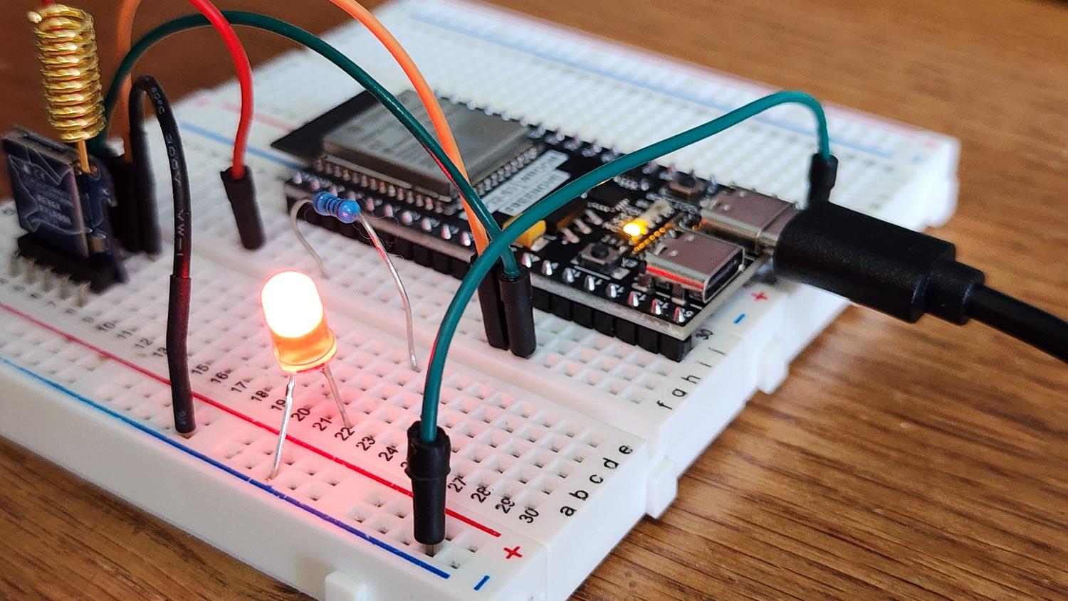 Prototipo electrónico en una placa de pruebas (breadboard) con el microcontrolador y un LED encendido, ilustrando la fase de montaje.