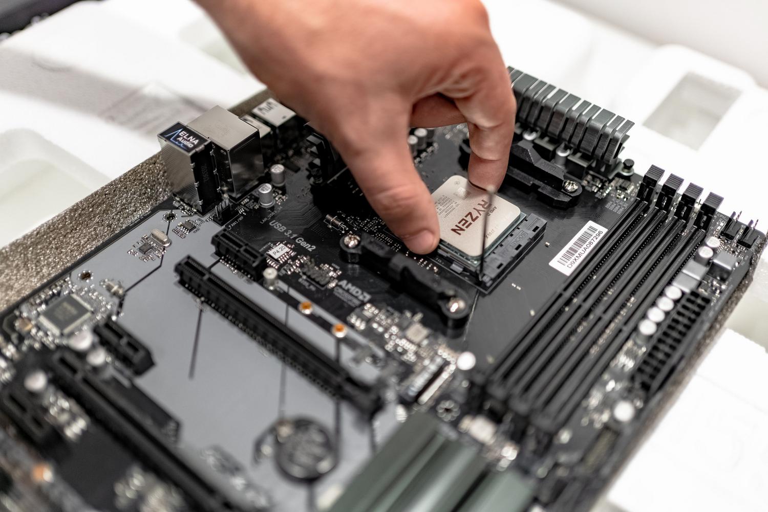Proceso de instalación de un procesador AMD Ryzen en una placa base moderna, representando el diagnóstico y montaje de hardware. Proceso de instalación de un procesador AMD Ryzen en una placa base moderna, representando el diagnóstico y montaje de hardware.