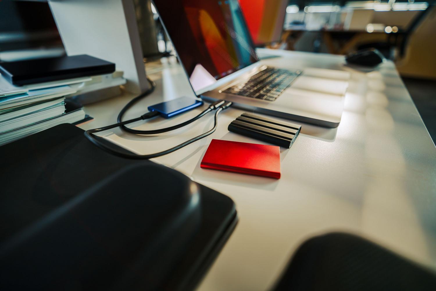 Escritorio de trabajo con laptop y discos duros externos para la realización de copias de seguridad de datos.