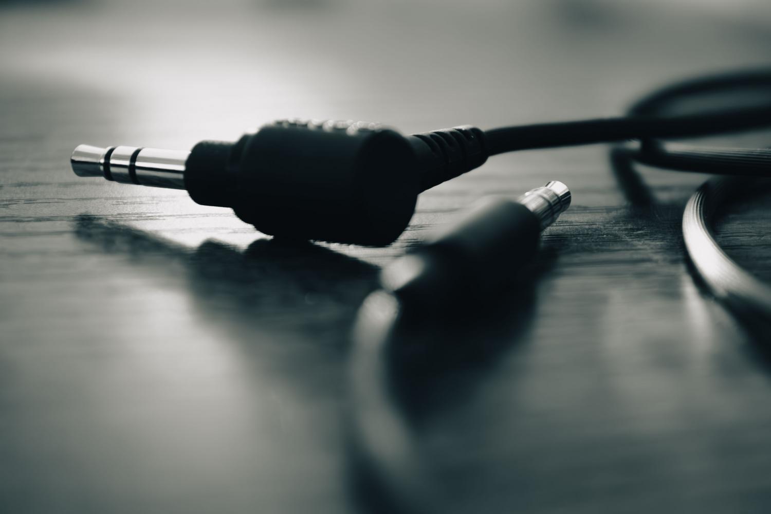 Primer plano de un conector jack de audio sobre una mesa de madera.