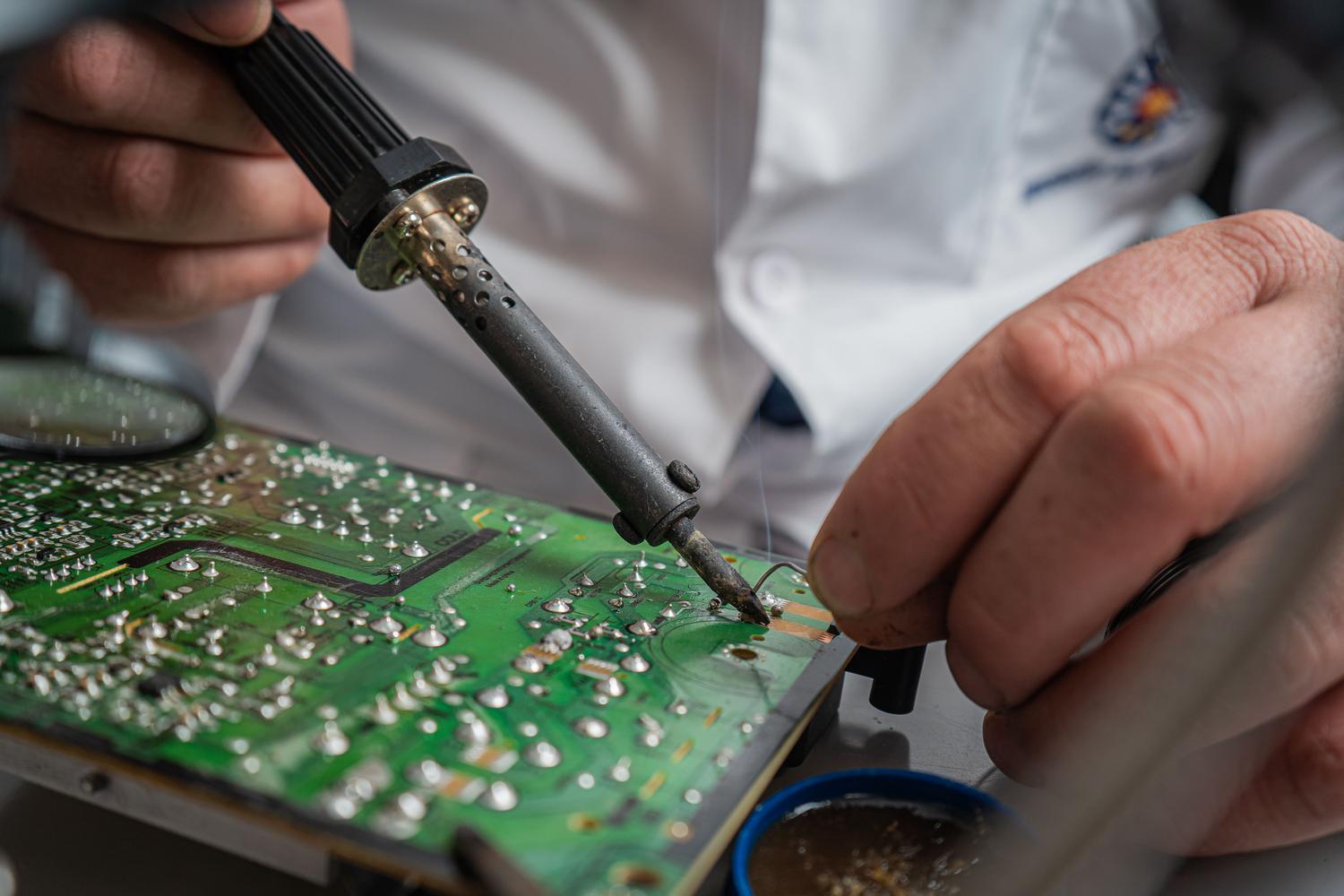 Técnico realizando un proceso de soldadura preciso en una placa de circuito electrónico.