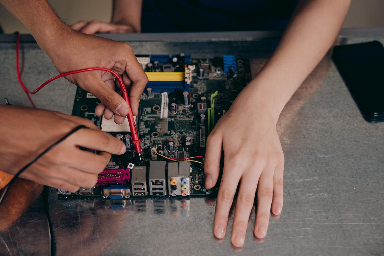 Técnico utilizando un multímetro digital para comprobar la continuidad eléctrica en una placa base, paso fundamental para el diagnóstico de puertos USB.