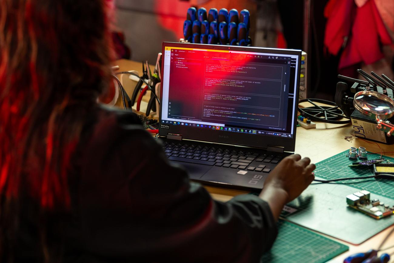 Programador escribiendo código en un ordenador portátil junto a herramientas de electrónica
