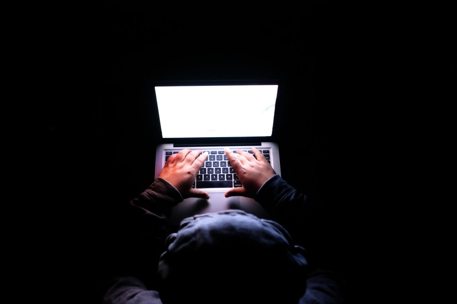Persona utilizando un portátil en un entorno oscuro enfatizando la privacidad, el anonimato y la seguridad online.