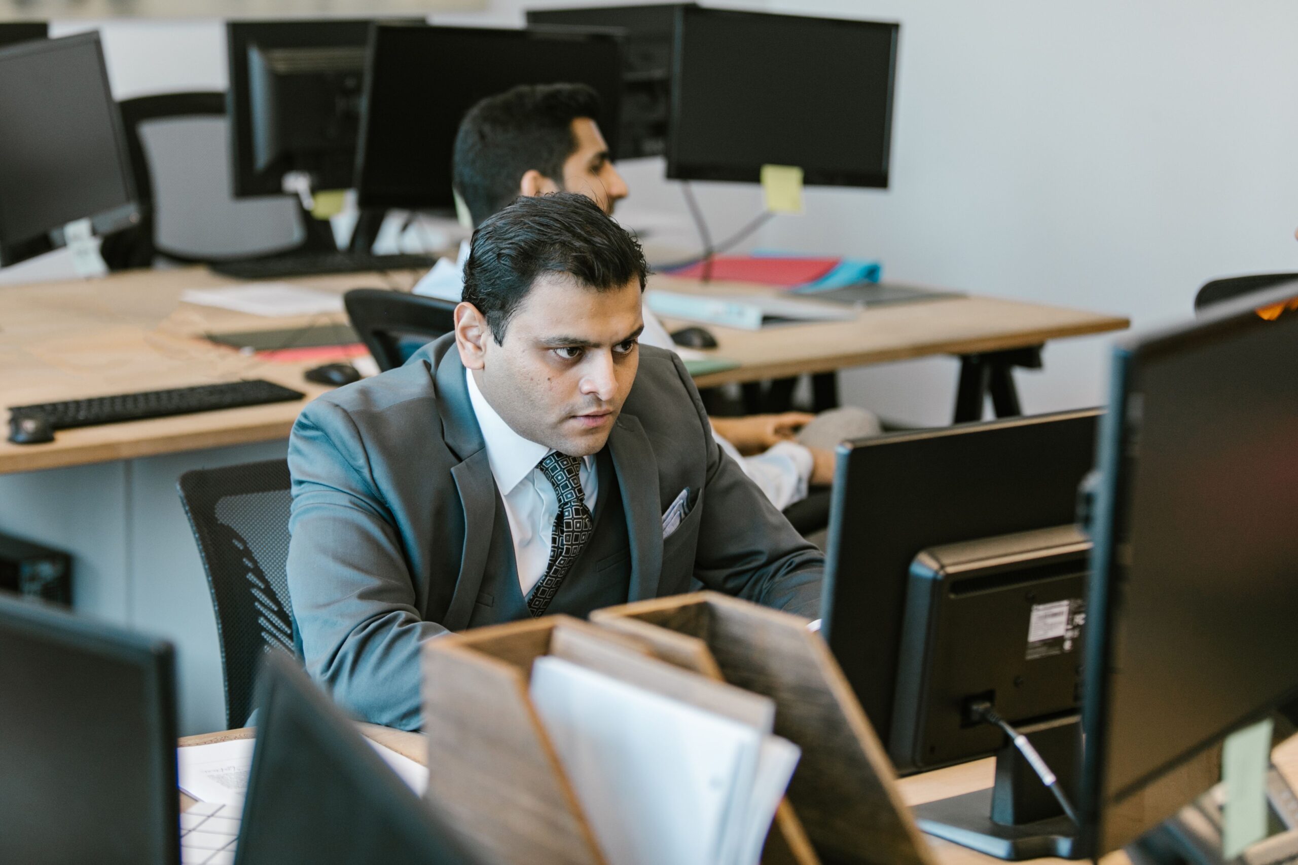 Hombre de negocios concentrado trabajando en un escritorio de oficina moderno, representando la resolución de problemas técnicos. Hombre de negocios concentrado trabajando en un escritorio de oficina moderno, representando la resolución de problemas técnicos.