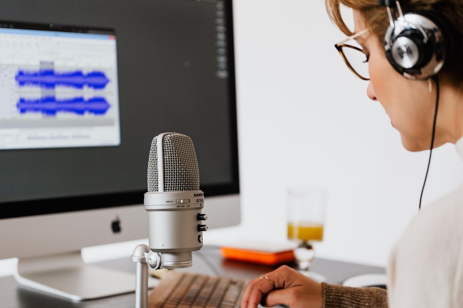 Mujer grabando audio en su oficina en casa con micrófono y software de edición