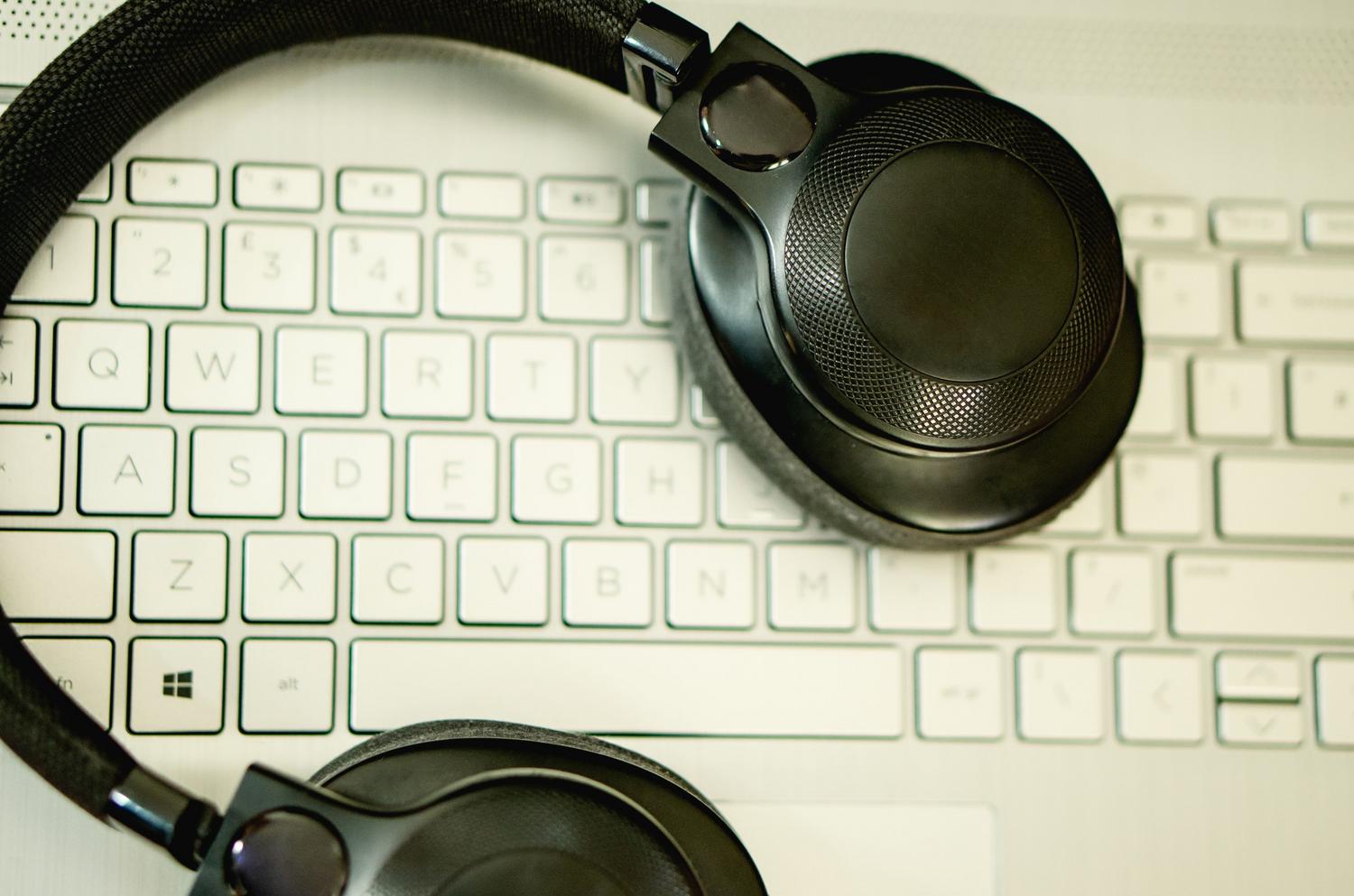 Auriculares descansando sobre un teclado de ordenador, representando la escucha y escritura en la transcripción