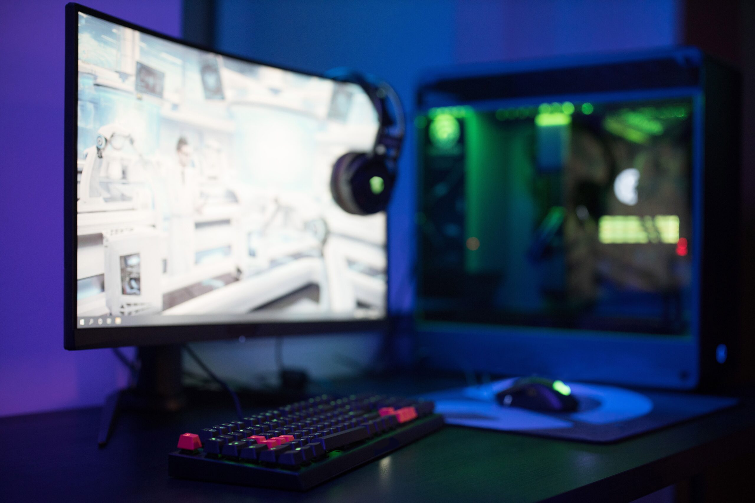 Setup de gaming moderno con monitor curvo y teclado RGB, ideal para monitorizar el rendimiento mientras se juega.