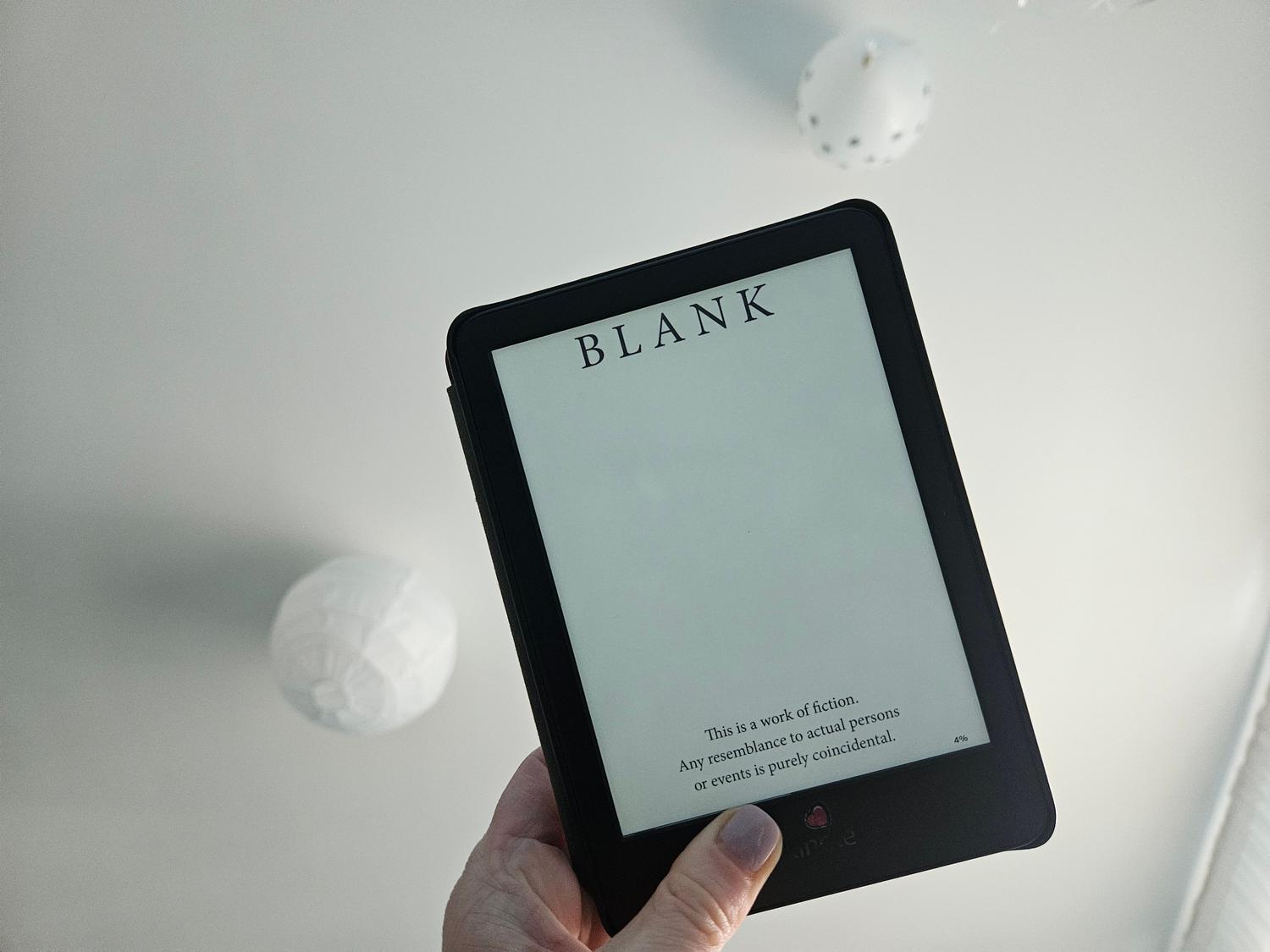Primer plano de una mano sosteniendo un lector electrónico con pantalla en blanco en una habitación minimalista, representando el inicio de un proyecto de jailbreak.