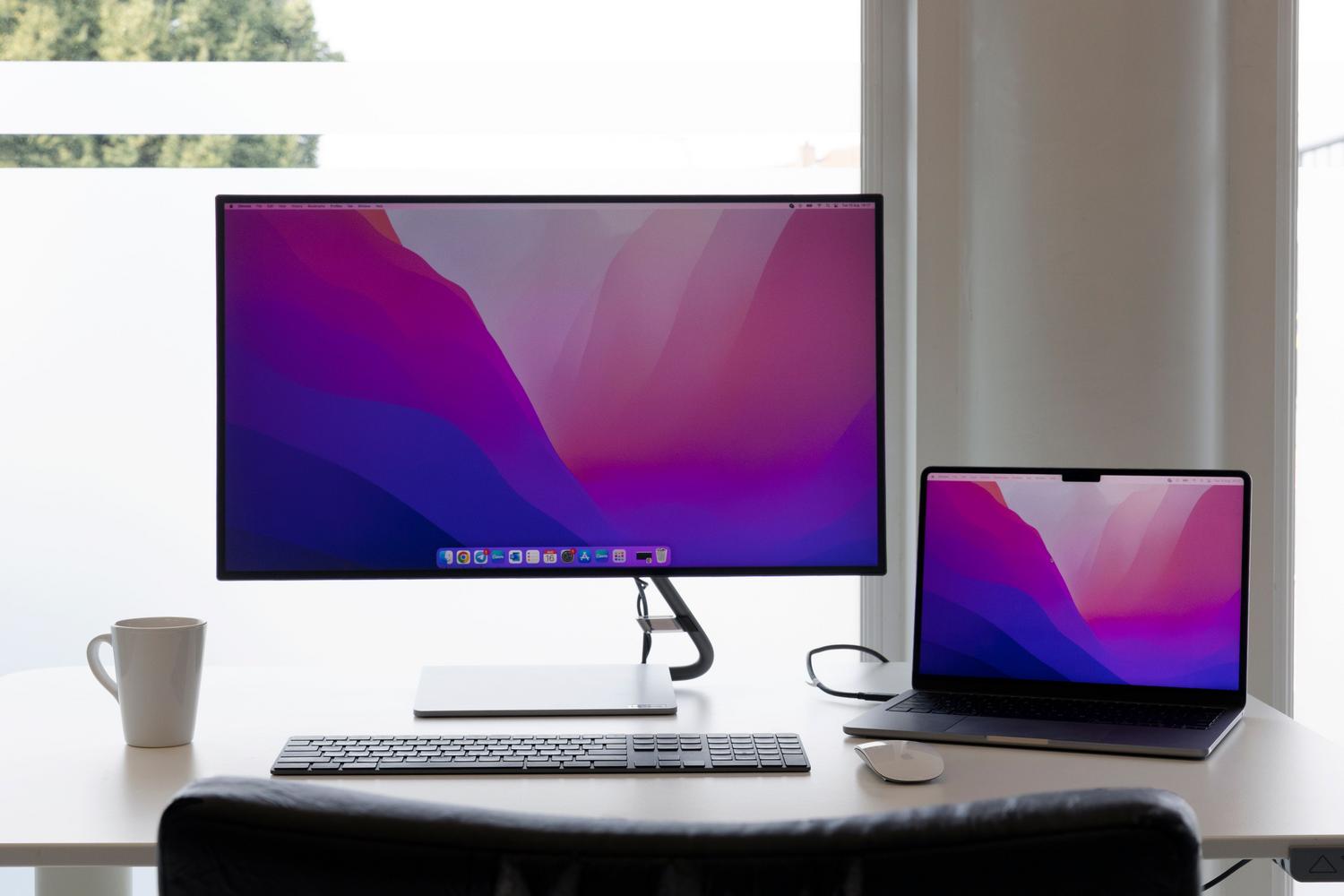 Espacio de trabajo minimalista con un portátil conectado a monitores externos. Espacio de trabajo minimalista con un portátil conectado a monitores externos.