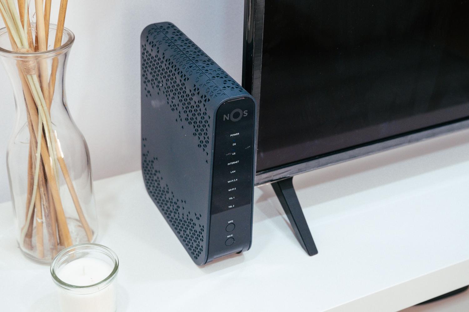 Router doméstico ubicado en un mueble del salón junto a un televisor