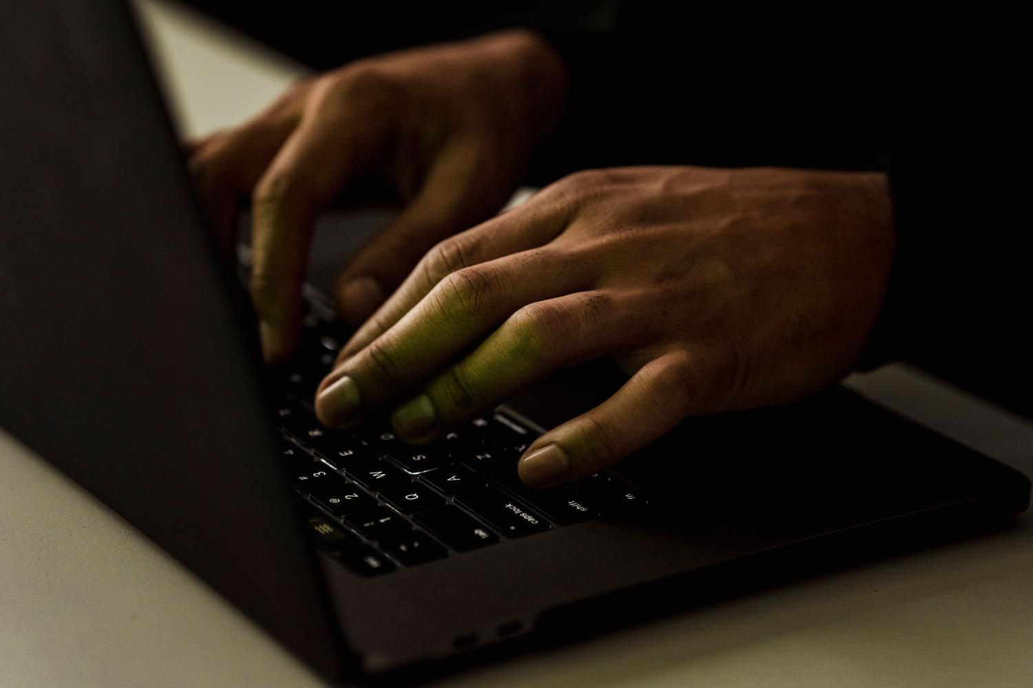 Persona programando en un entorno oscuro, enfocándose en la interacción física con el teclado para el uso de comandos.