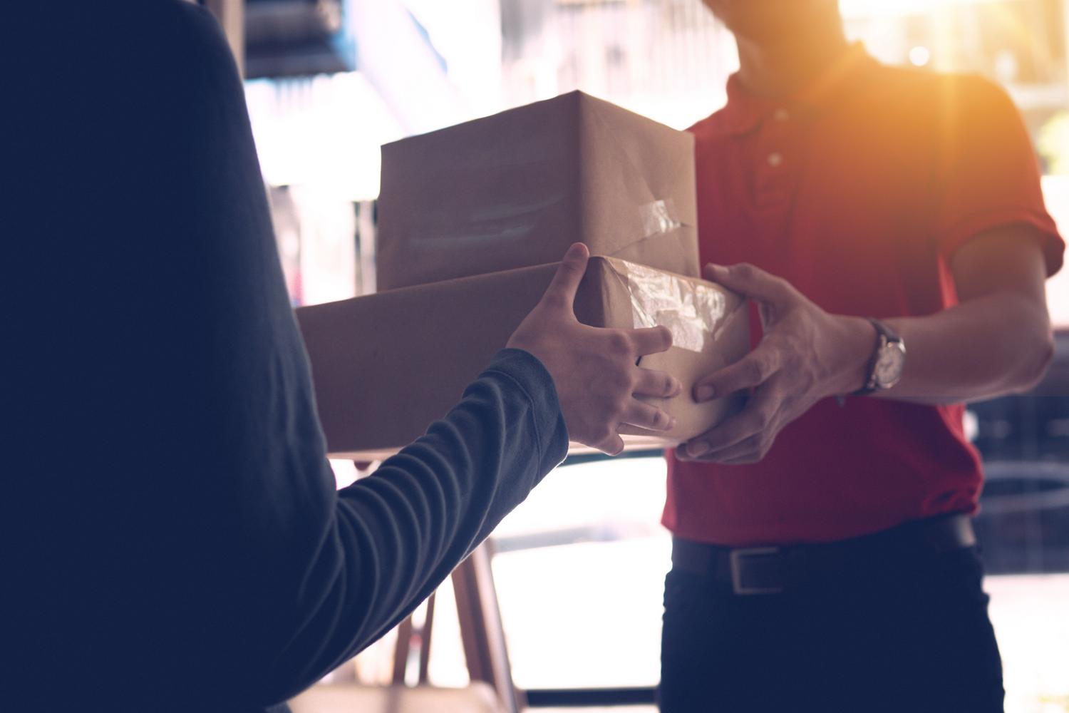 Momento final de la entrega donde un repartidor profesional entrega los paquetes directamente al cliente.