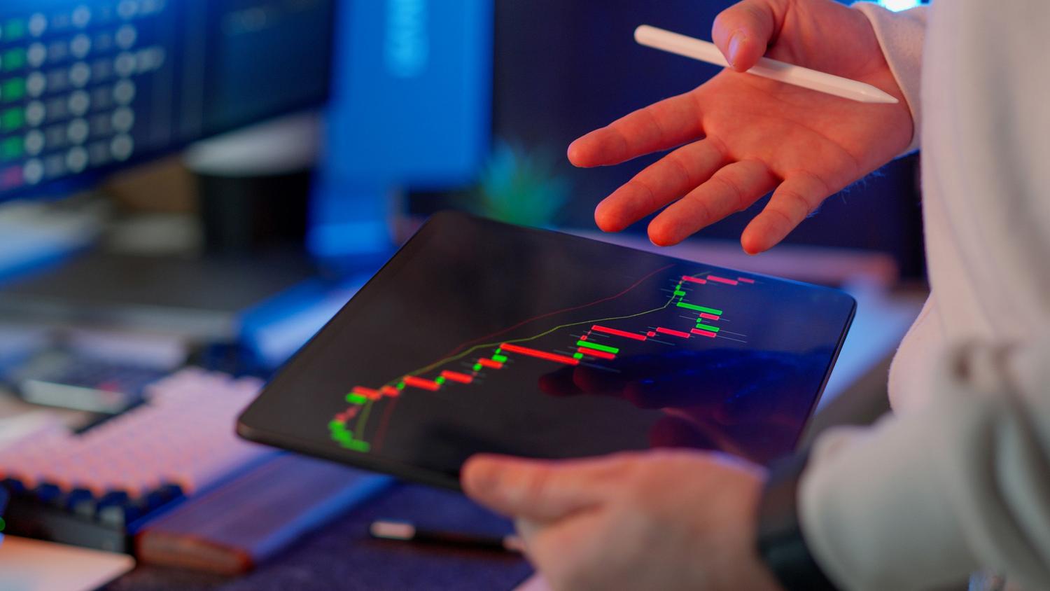 Primer plano de una persona analizando gráficos financieros en una tablet, representando la toma de decisiones basada en datos en tiempo real.