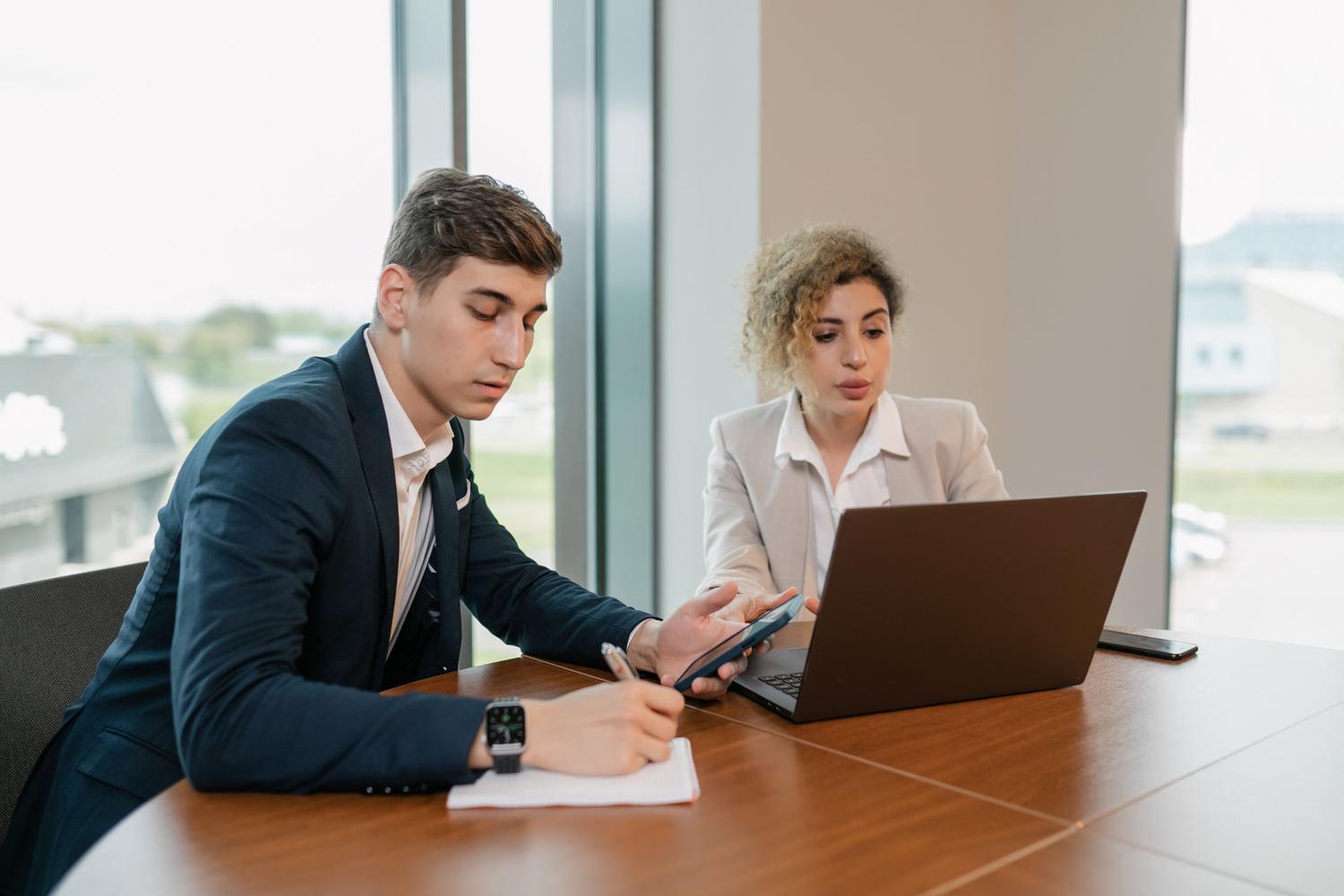 Equipo de profesionales colaborando con laptops y smartphones en una oficina moderna, ilustrando la agilidad y el trabajo en la nube.