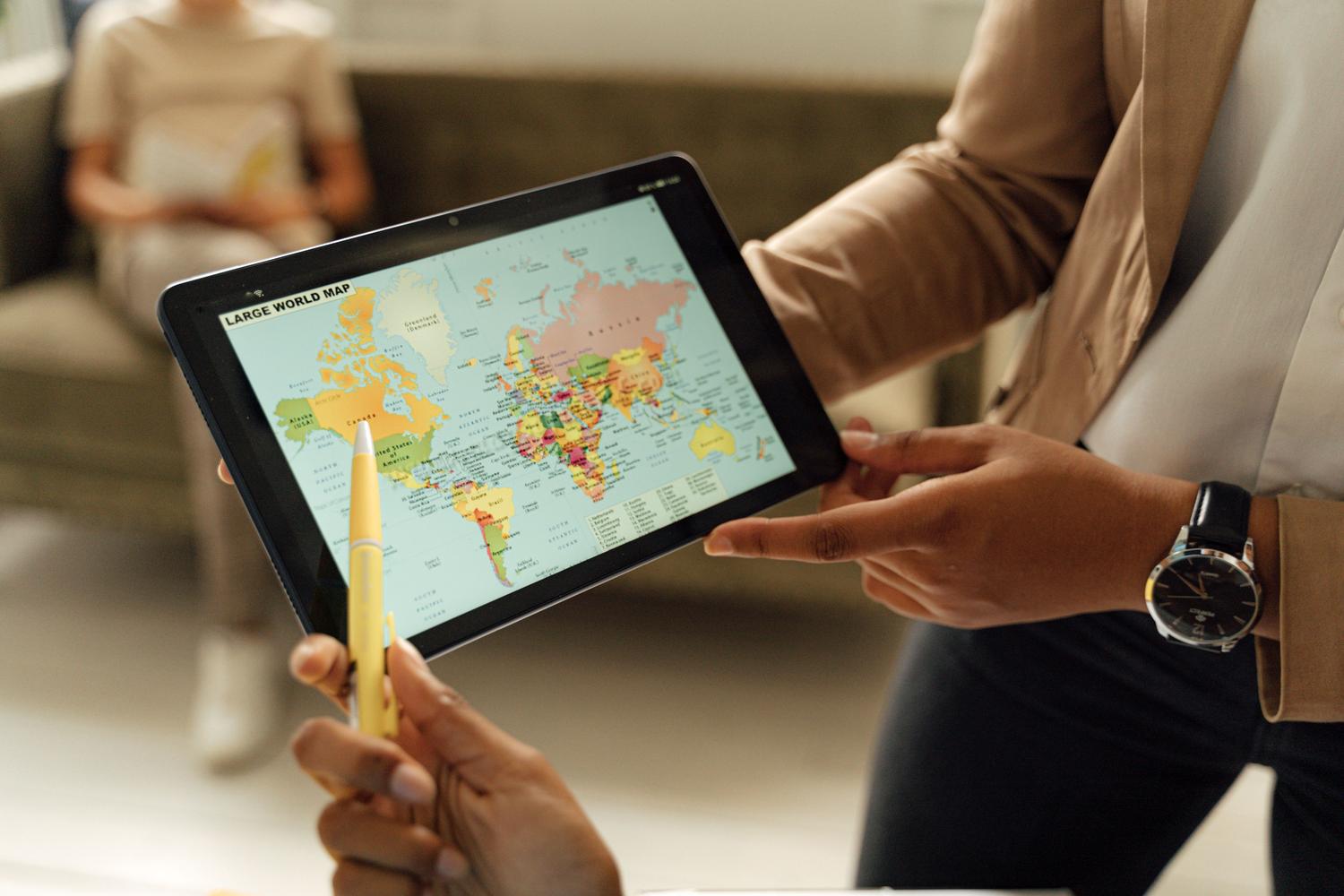 Taong nakikipag-ugnayan sa isang mapa ng mundo sa isang tablet, na naglalarawan ng kakayahang malampasan ang mga paghihigpit sa heograpiya.