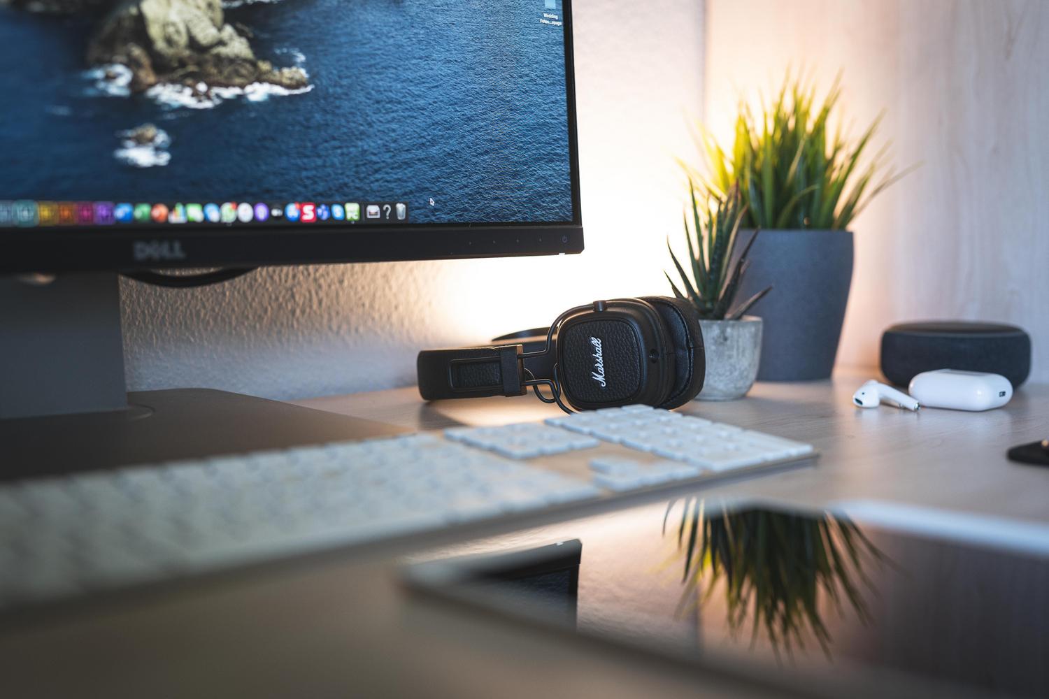 Escritorio minimalista con monitor y auriculares, proporcionando un contexto tecnológico limpio
