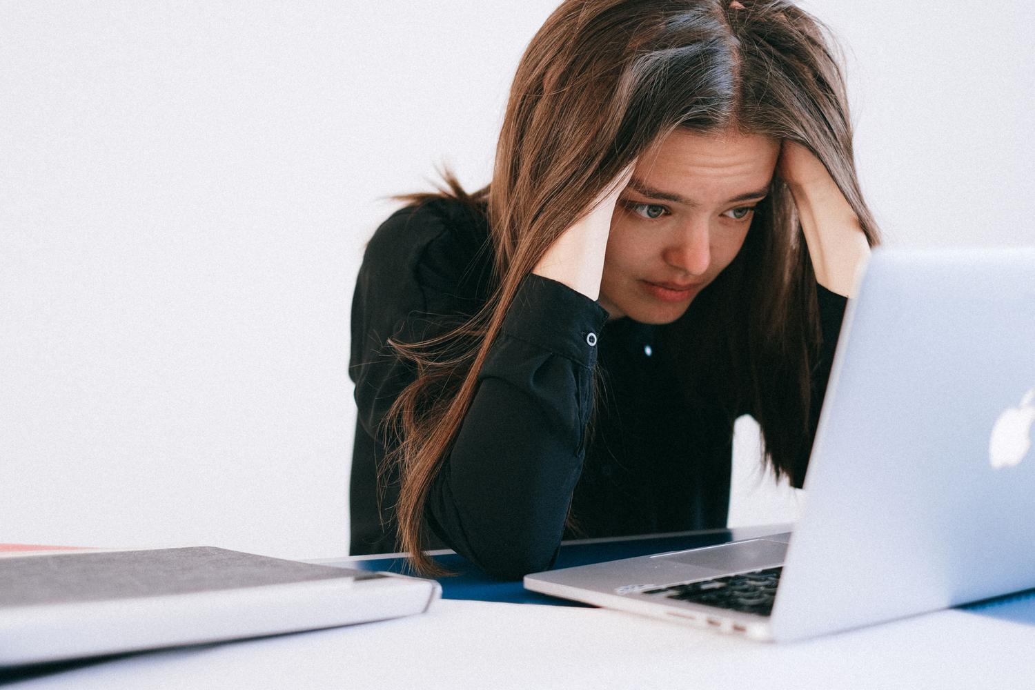 Mujer estresada mirando la pantalla de su ordenador portátil con expresión de preocupación.