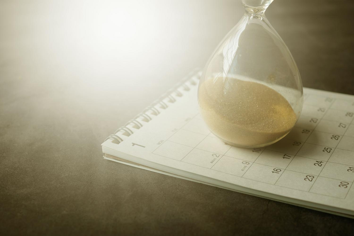 Reloj de arena sobre un calendario, simbolizando la eficiencia y la gestión del tiempo en rutinas diarias. Reloj de arena sobre un calendario, simbolizando la eficiencia y la gestión del tiempo en rutinas diarias.