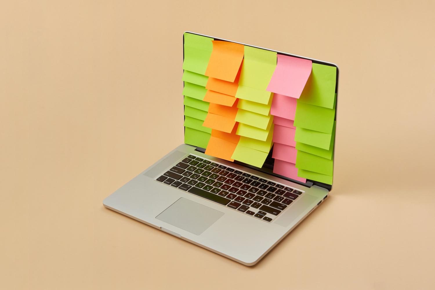 Portátil con notas adhesivas coloridas en pantalla, simbolizando el proceso de organizar el caos mental y la transición hacia un sistema de notas estructurado.