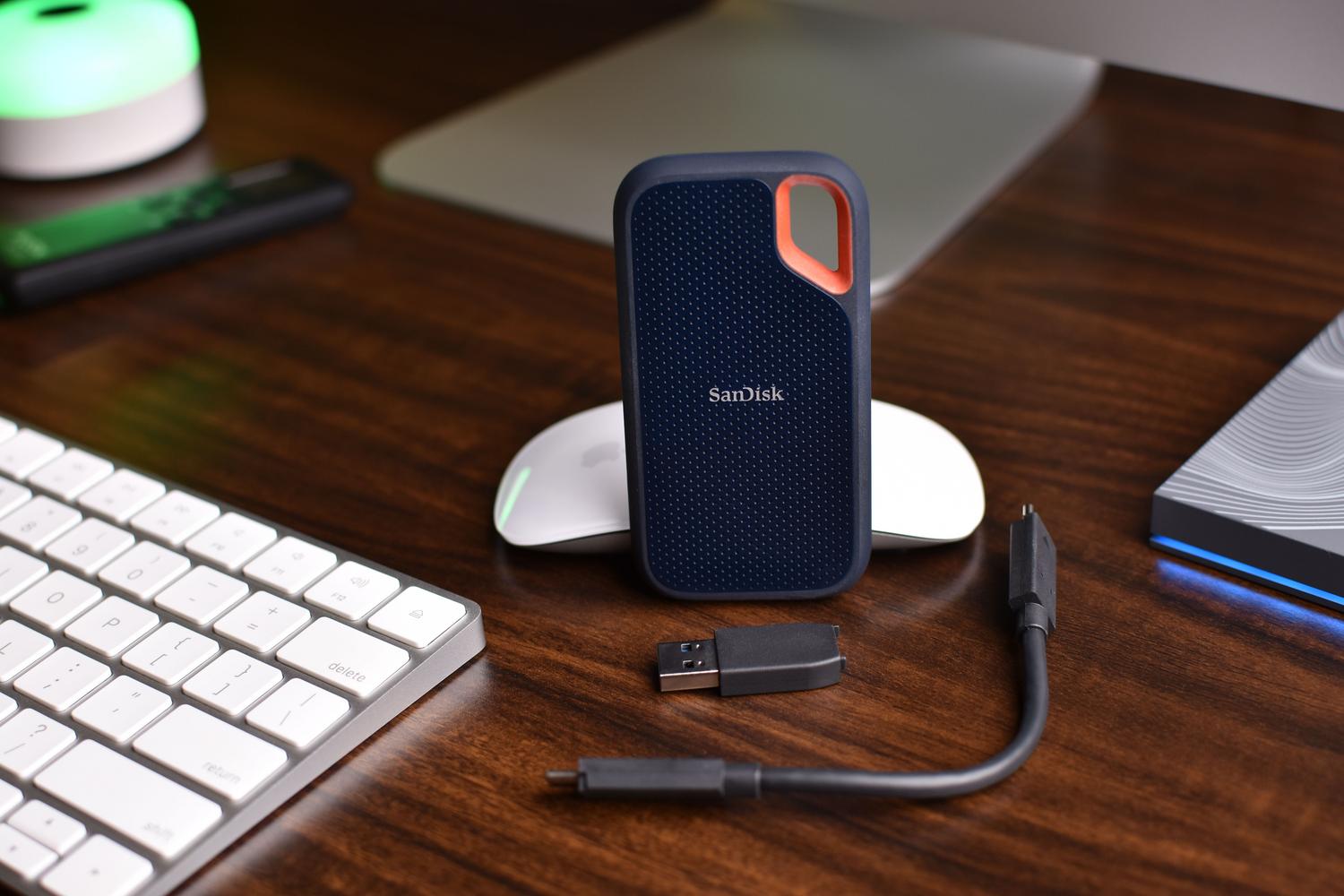 SSD portátil de alta velocidad con sus cables de conexión USB sobre un escritorio de madera. SSD portátil de alta velocidad con sus cables de conexión USB sobre un escritorio de madera.